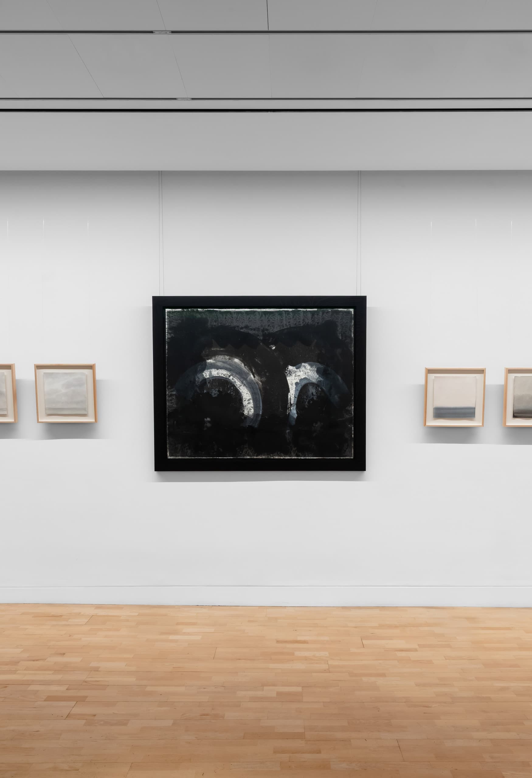 Bilder an einer weißen Wand, mittig ein großes schwarzes.