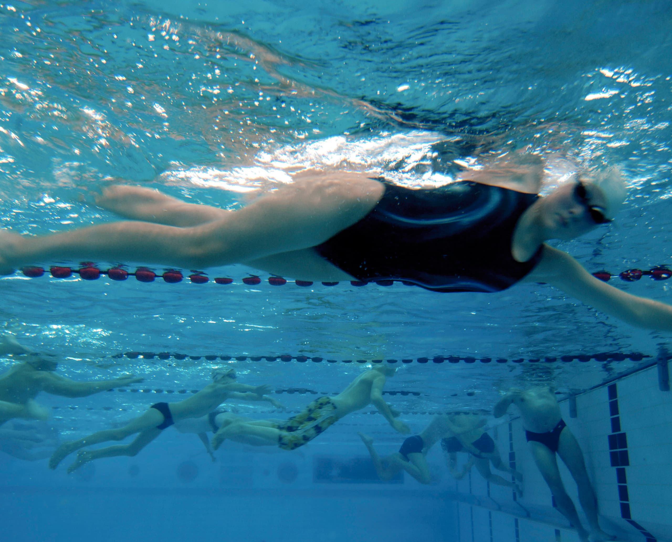 Unterwasseransicht von Schwimmern in der Olympia Schwimmhalle, beleuchtet mit ERCO Focalflood Flutern.