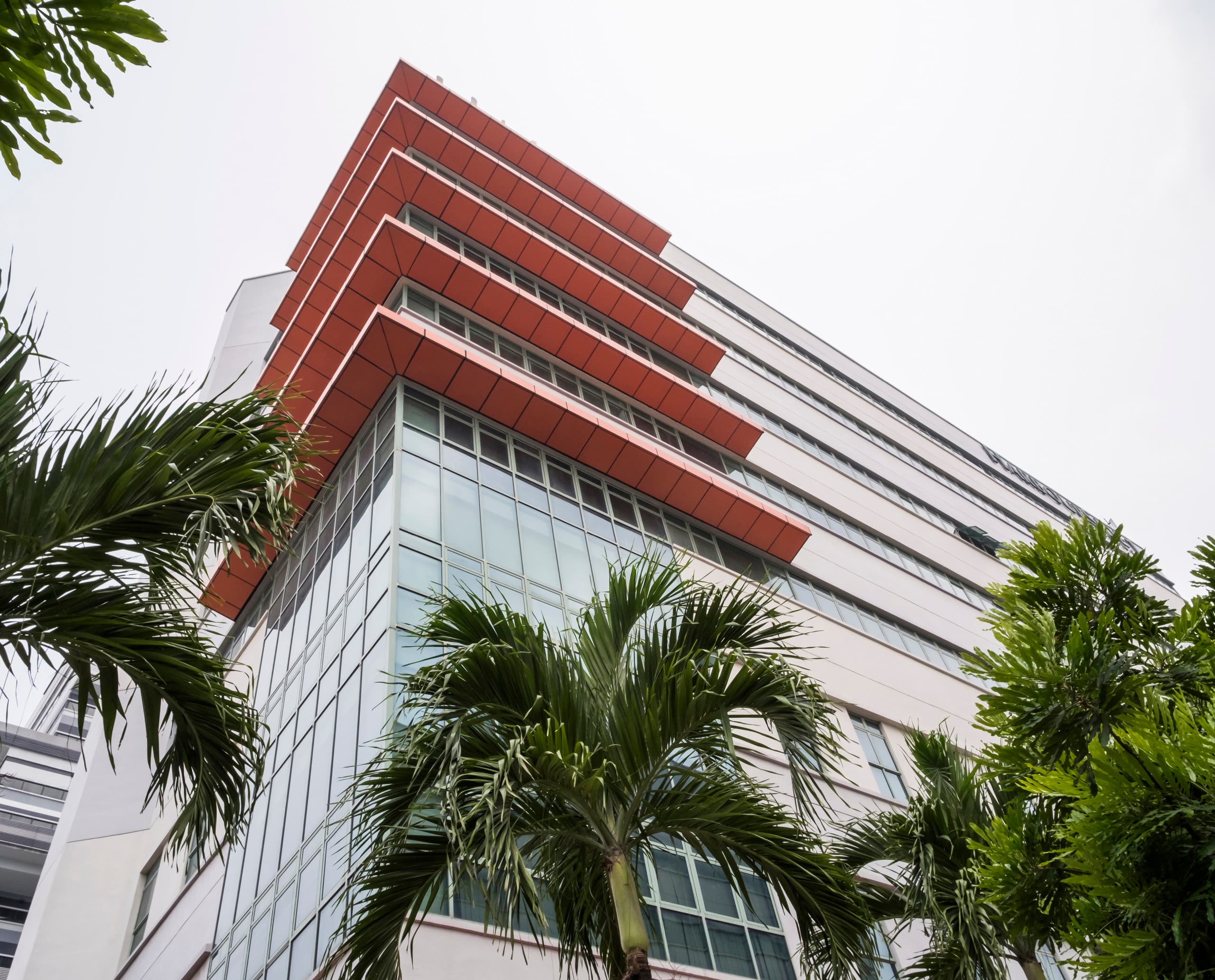 LuxLight Bürogebäude in Singapur mit ERCO LED-Beleuchtung, die die orangefarbene Fassade hervorhebt.