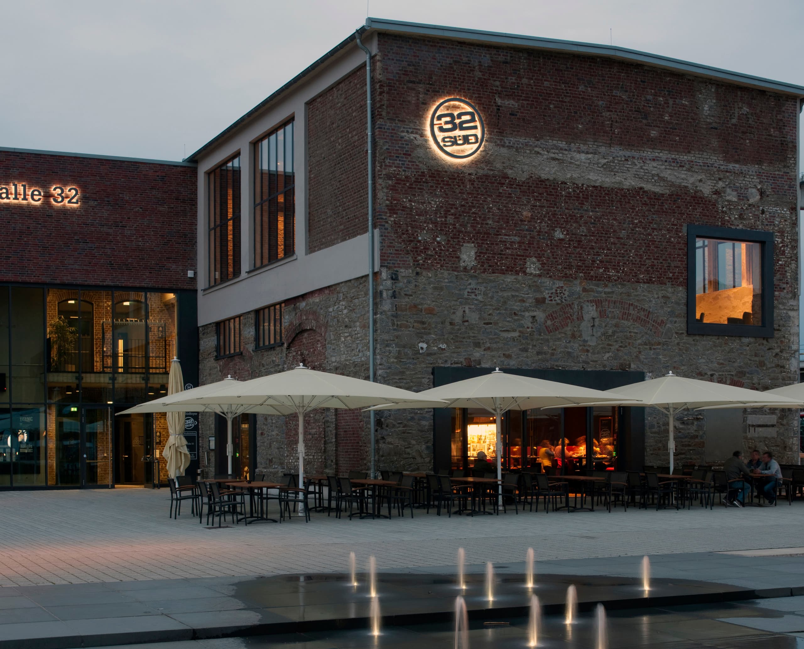 Halle 32 Restaurant in Gummersbach mit ERCO LED-Beleuchtung, die die Industriearchitektur hervorhebt.
