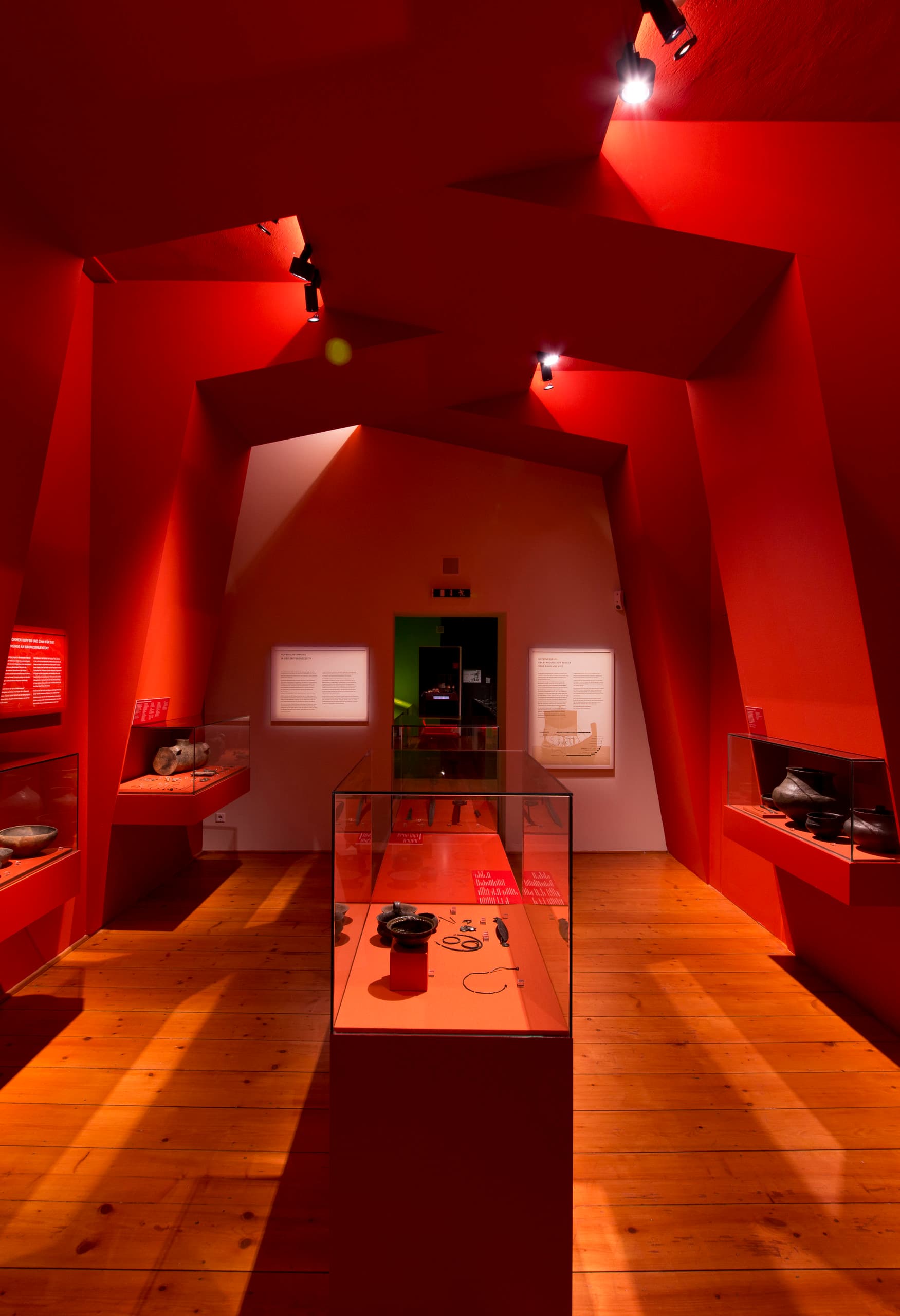 Roter Ausstellungsraum im MAMUZ Museum Mistelbach mit archäologischen Fundstücken, beleuchtet mit ERCO Strahlern.