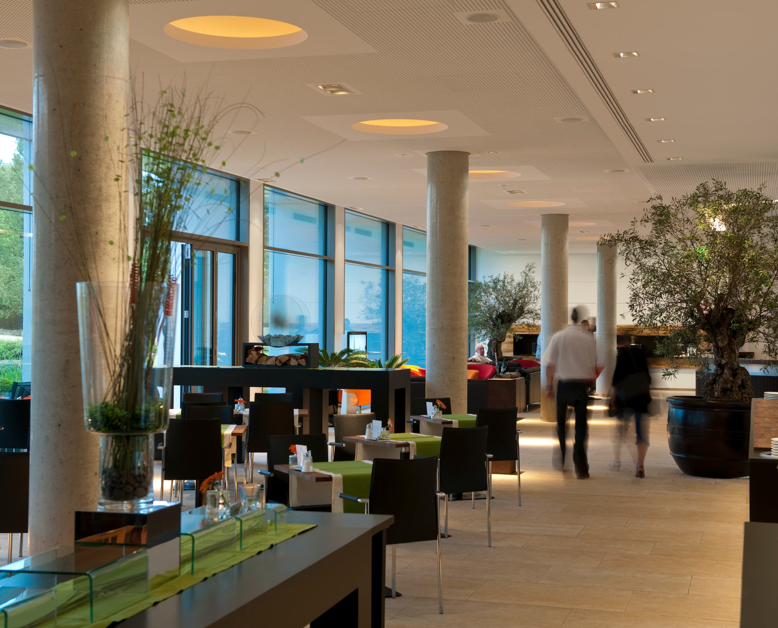 Helle, einladende Hotellobby im LAGO Hotel Ulm mit stilvoller Beleuchtung und Pflanzen.