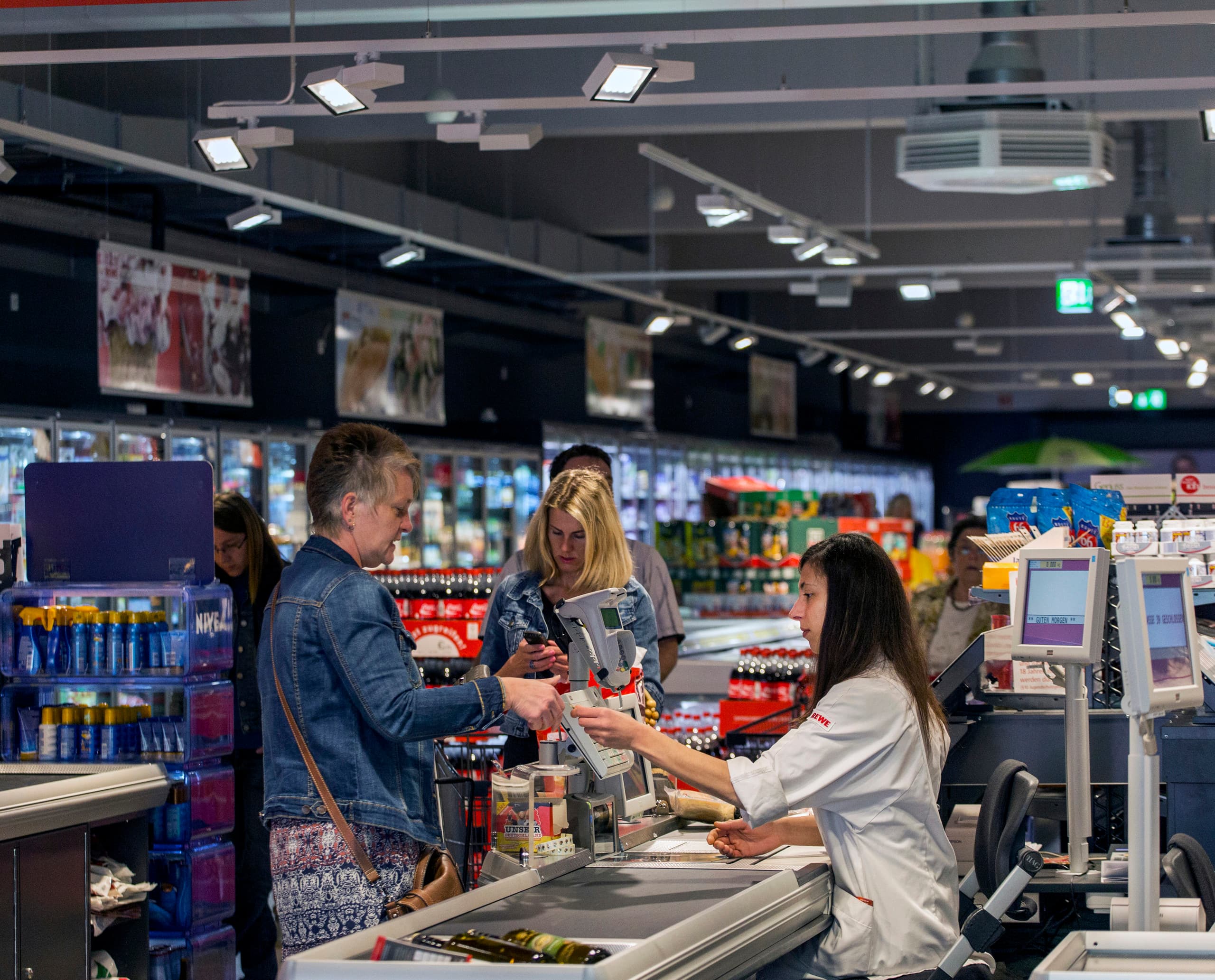 REWE-Supermarkt Kasse mit Opton LED-Akzentbeleuchtung für Energieeffizienz.