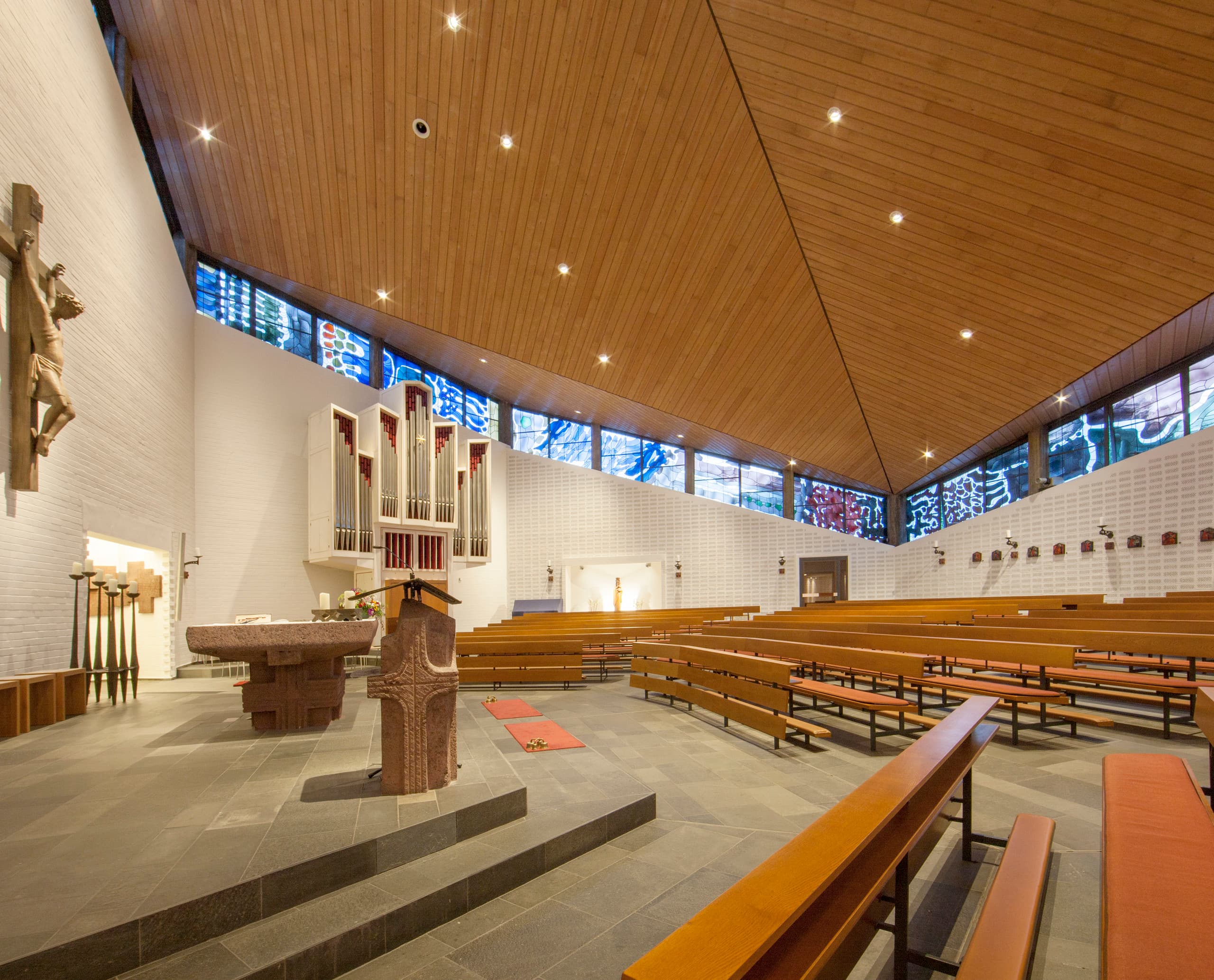 Innenraum einer Kirche mit Bänken, Altar und Orgel, beleuchtet mit ERCO Lichtwerkzeugen für eine kontemplative Atmosphäre.