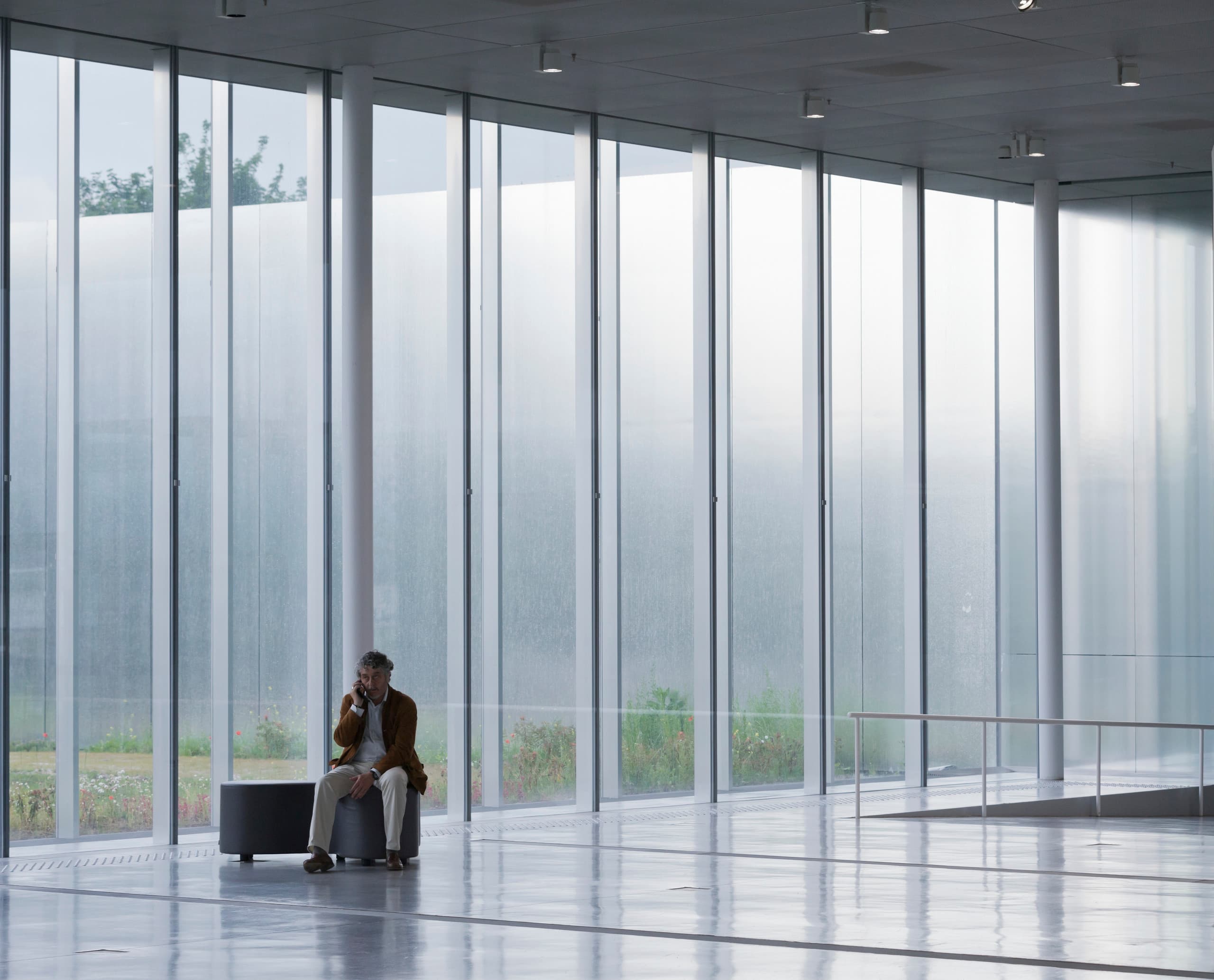 Mann telefoniert im hellen Louvre Lens Museum, das durch ERCO LED Leuchten beleuchtet wird.