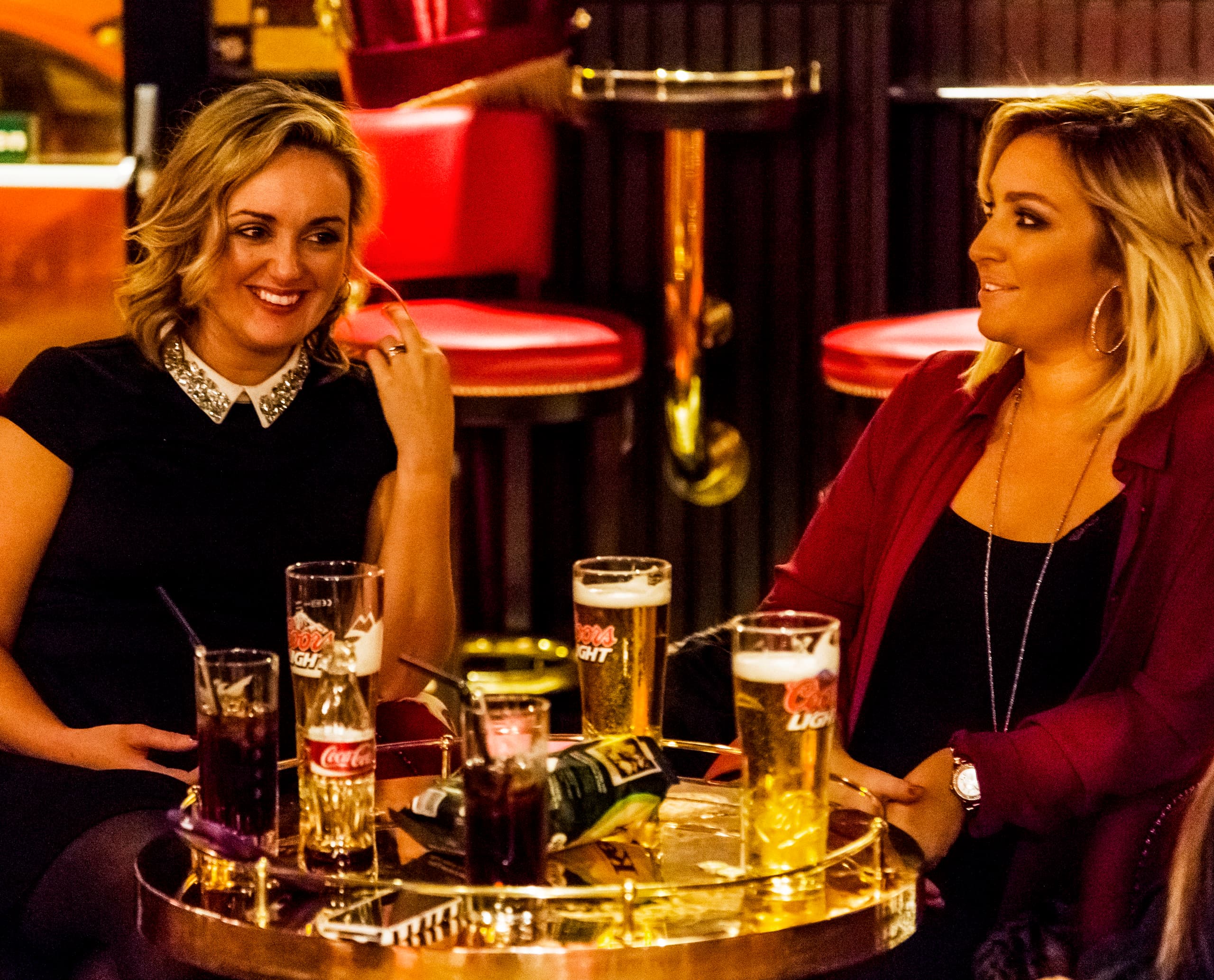 Frauen genießen Getränke in der stimmungsvollen Harp Bar, Belfast, beleuchtet mit ERCO LED-Leuchten.