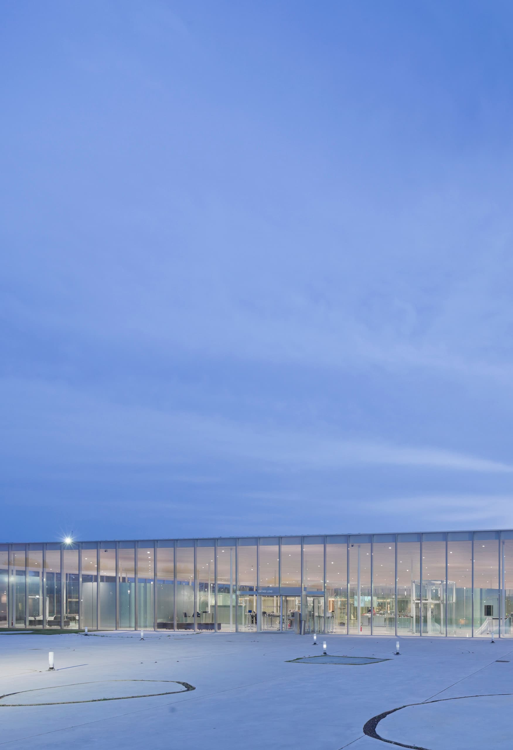 Louvre-Lens Museum bei Dämmerung, beleuchtet mit ERCO LED-Licht für eine transparente und einladende Atmosphäre.