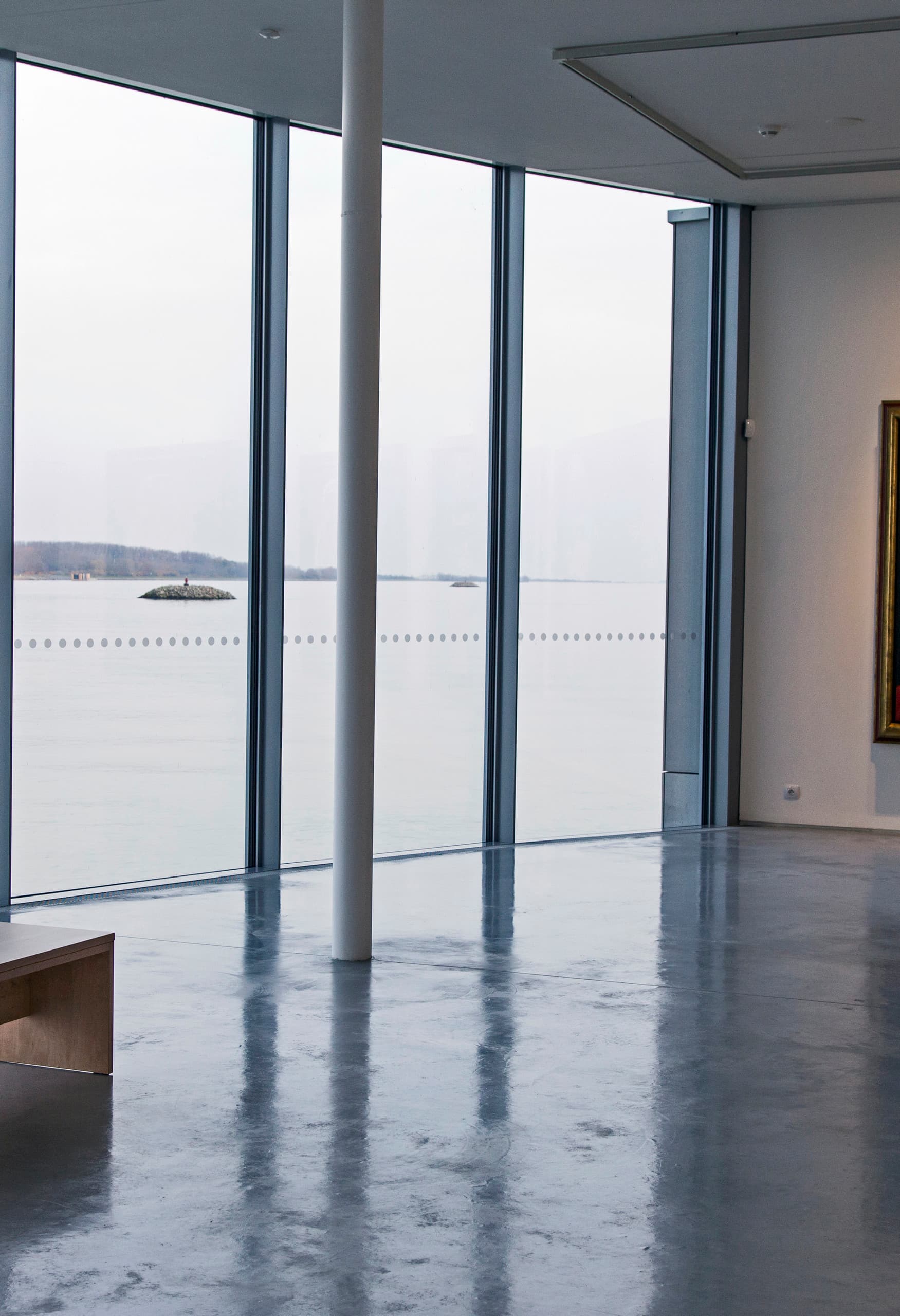 Frau sitzt im Danubiana Museum und betrachtet die Donau durch die Fenster.