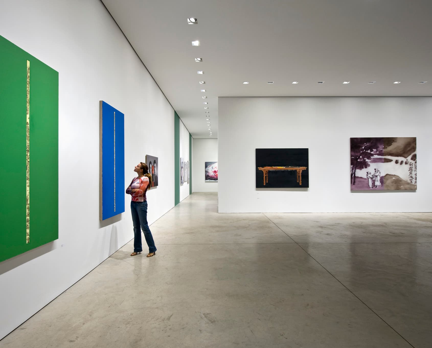 Frau betrachtet Kunst in einer Galerie mit Wallwashing, die Helligkeit und visuellen Komfort erhöht.