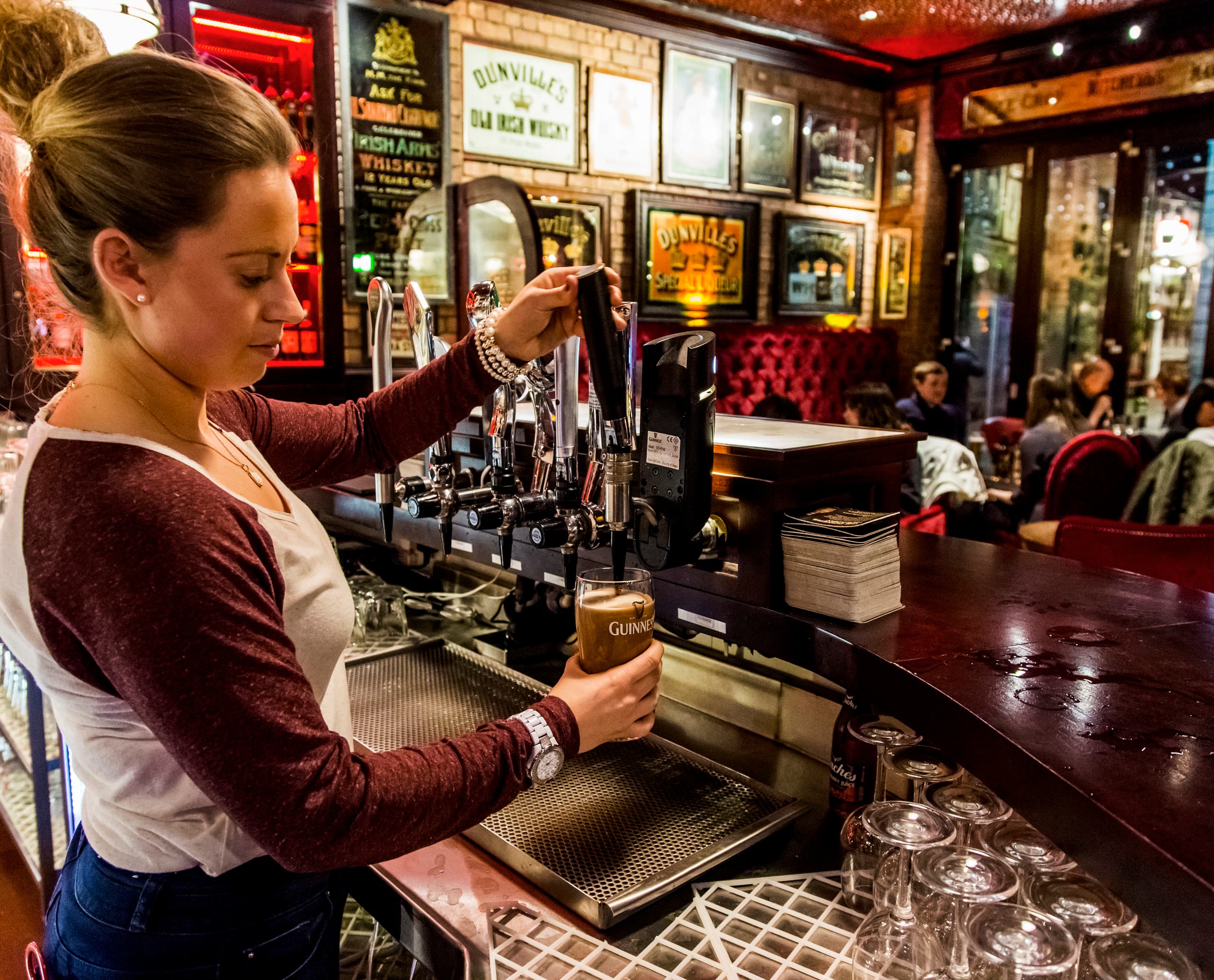 Zapfen von Guinness in der Harp Bar, Belfast, mit LED-Beleuchtung für traditionelle Pub-Atmosphäre.