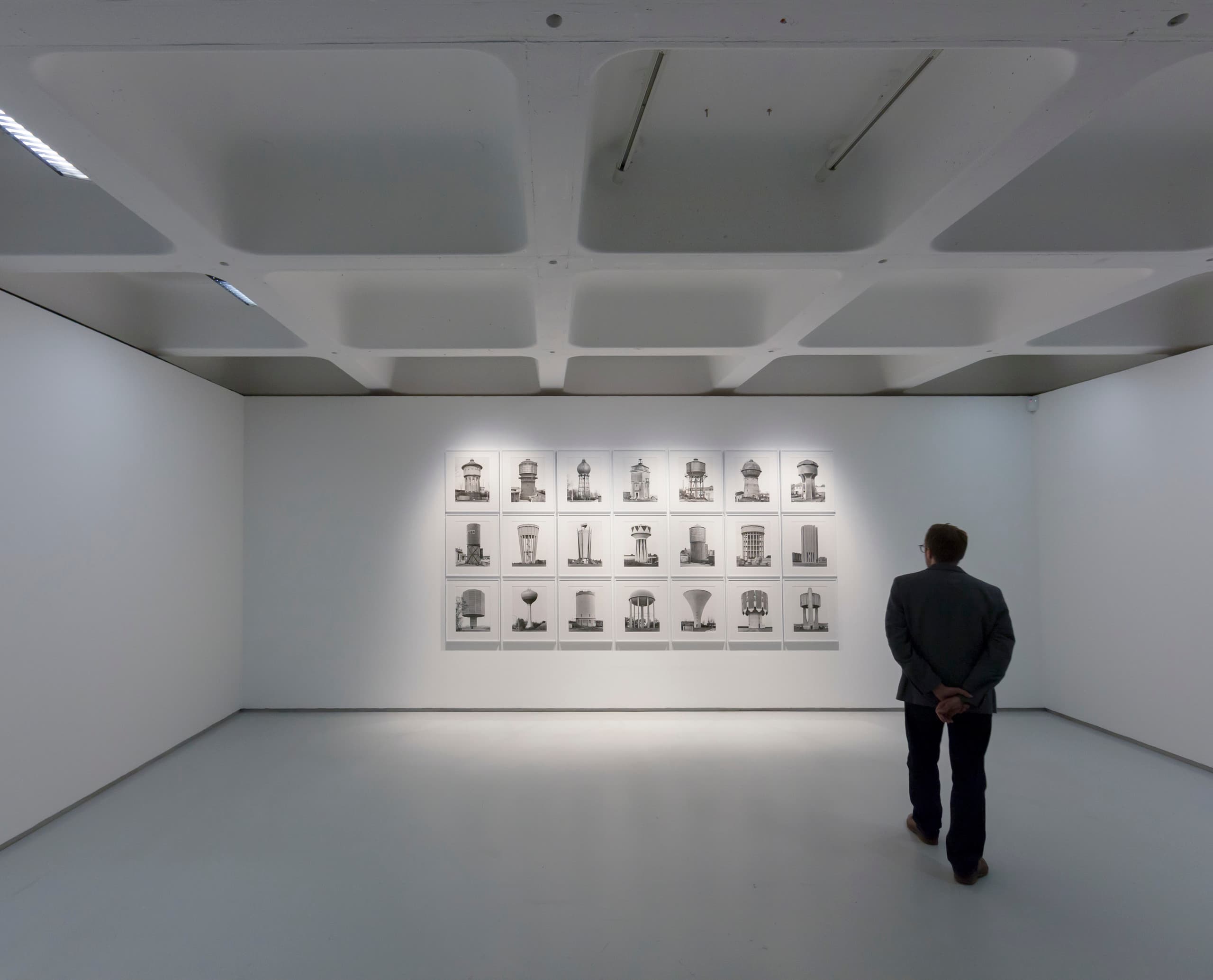 Mann betrachtet Kunstwerke in der Barbican Art Gallery, beleuchtet mit ERCO LED-Leuchten.