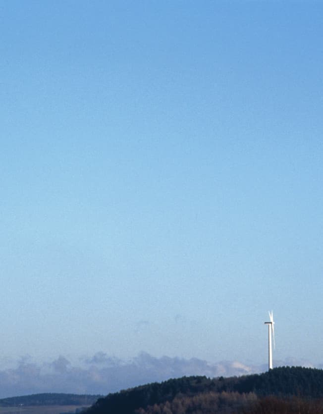 Windrad unter blauem Himmel, Symbol für Tageslicht und Energie.