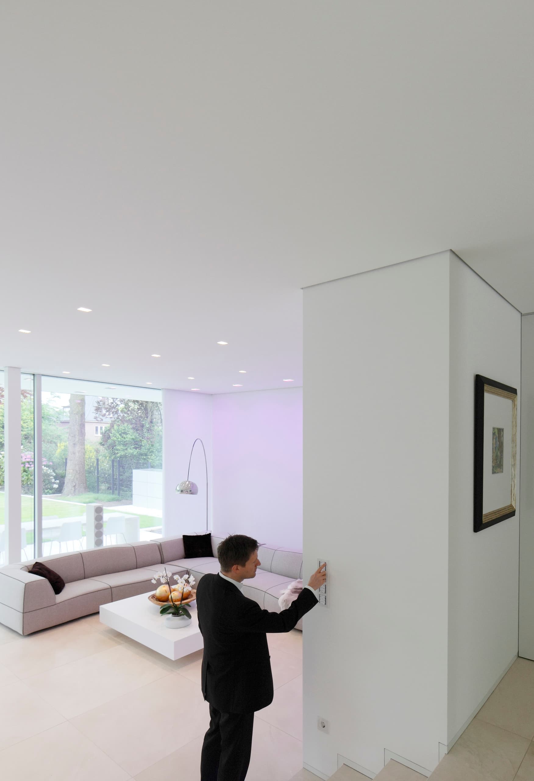 Mann bedient ERCO Lichtsteuerung in Villa Linari, Hamburg. Ambiente mit LED-Technik.