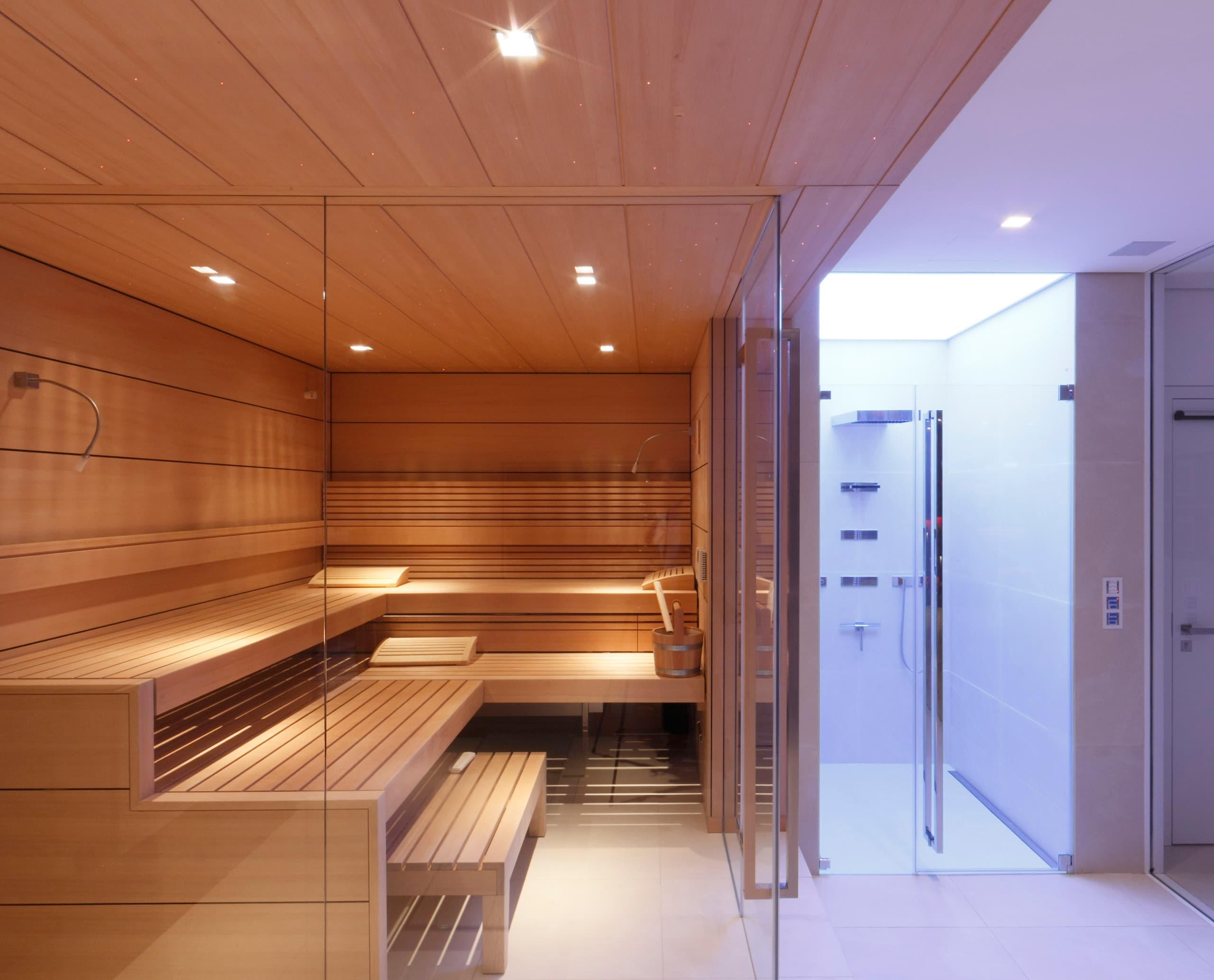Innenarchitektur einer Sauna mit Holzbänken und Glaswänden, beleuchtet mit ERCO LED-Leuchten.