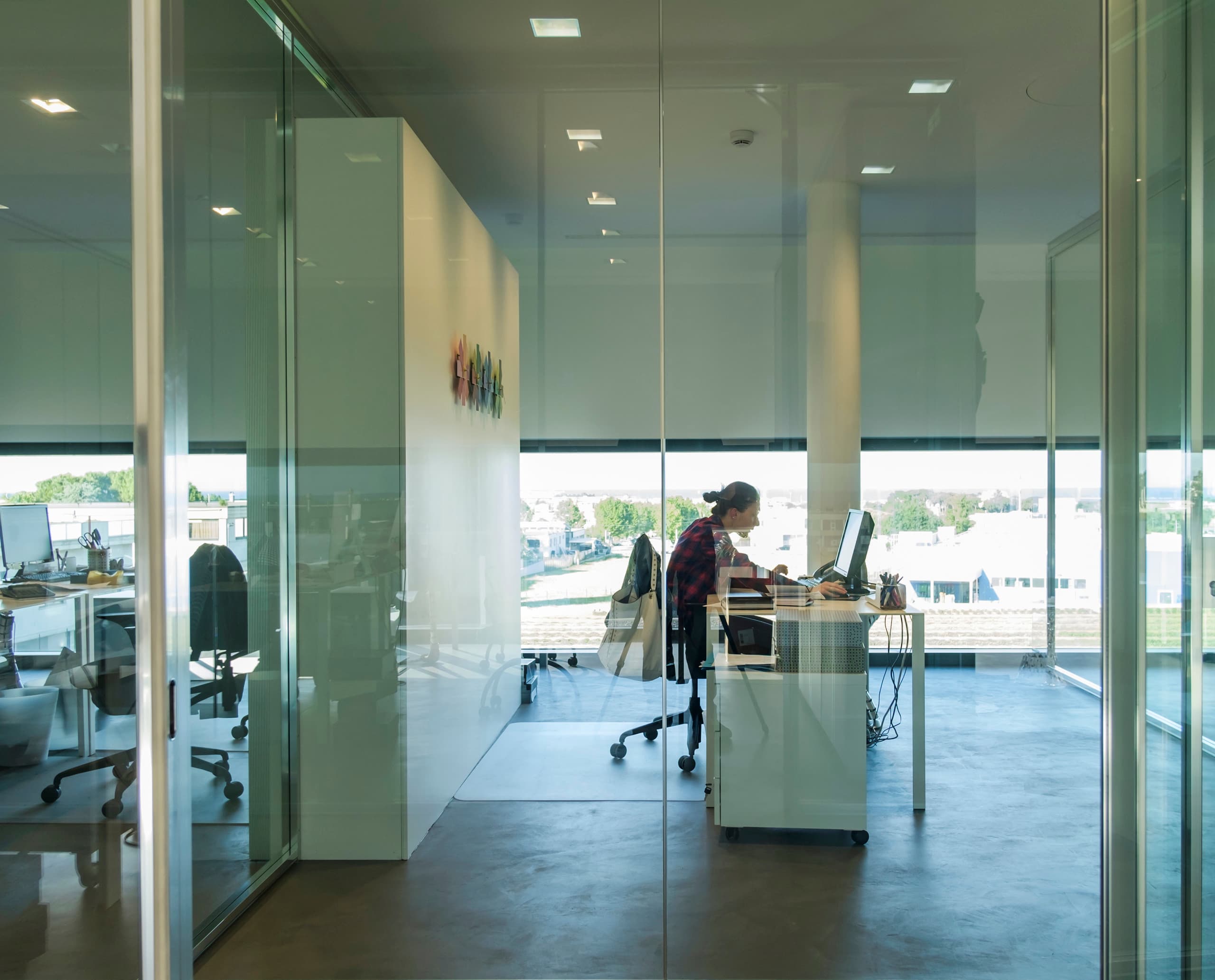 Le Silla Büro mit ERCO Beleuchtung: Mitarbeiterin am Schreibtisch in moderner Büroumgebung.