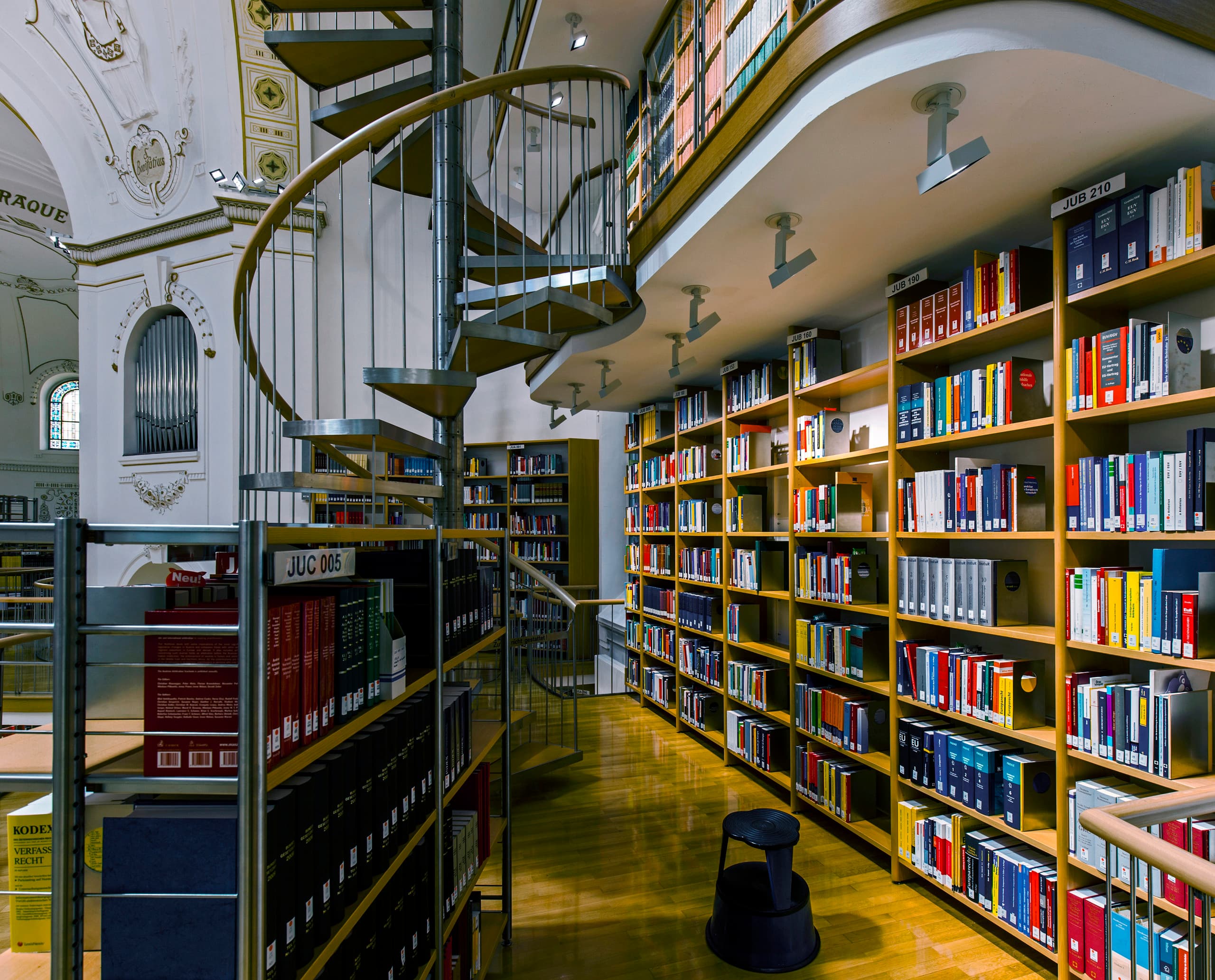 ERCO LED-Beleuchtung in der Vorarlberger Landesbibliothek mit Bücherregalen und Wendeltreppe.