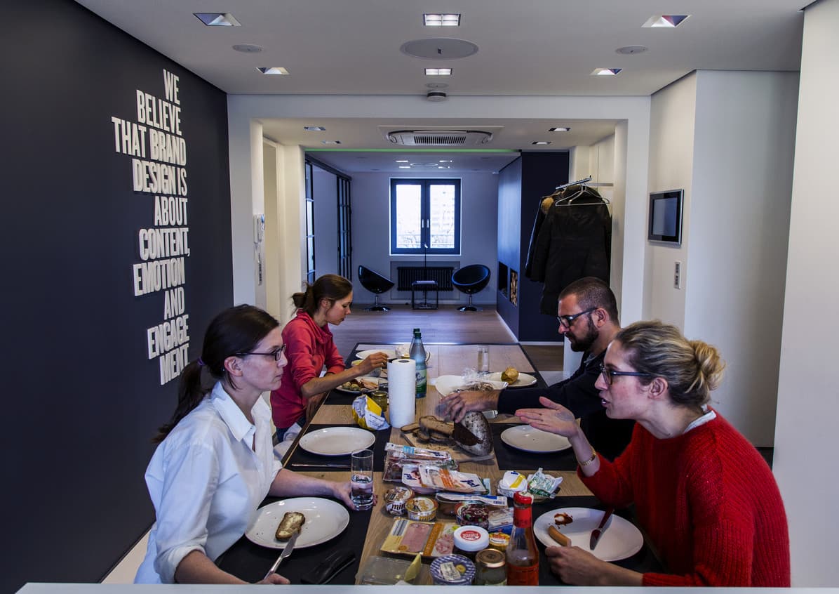 Team-Frühstück im modernen Büro mit ERCO Lichtlösungen für angenehme Arbeitsatmosphäre.
