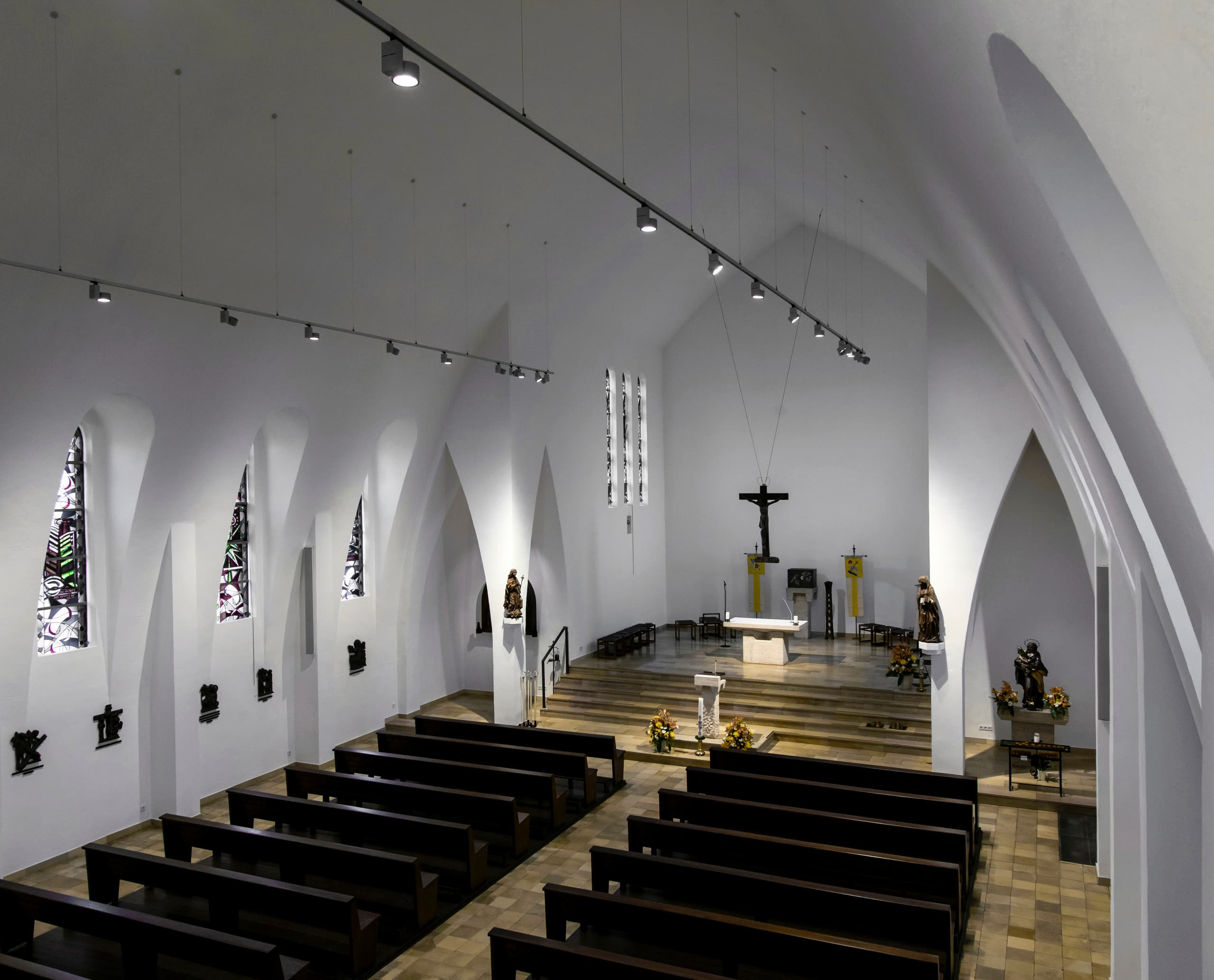 Innenansicht der St. Mariä Geburt Kirche mit ERCO Strahlern auf Schienen, die den Raum beleuchten.