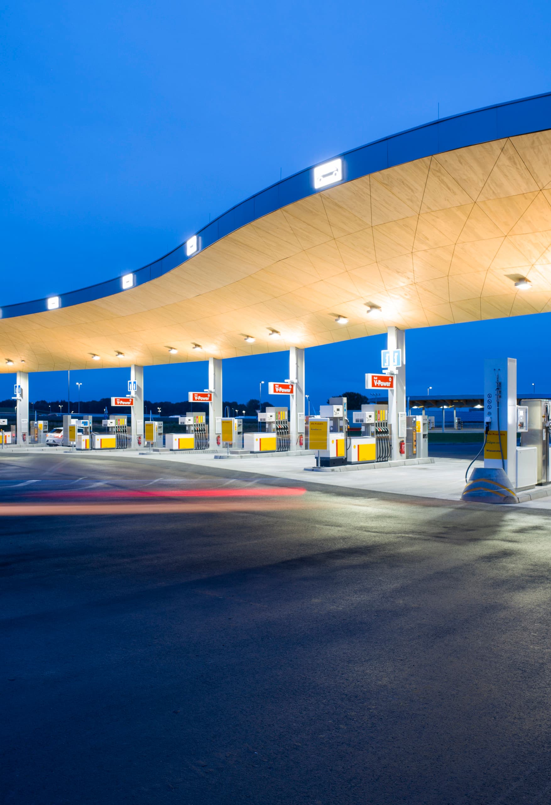 Beleuchtete Fürholzen Tankstelle mit geschwungenem Dach, entworfen mit ERCO Licht.