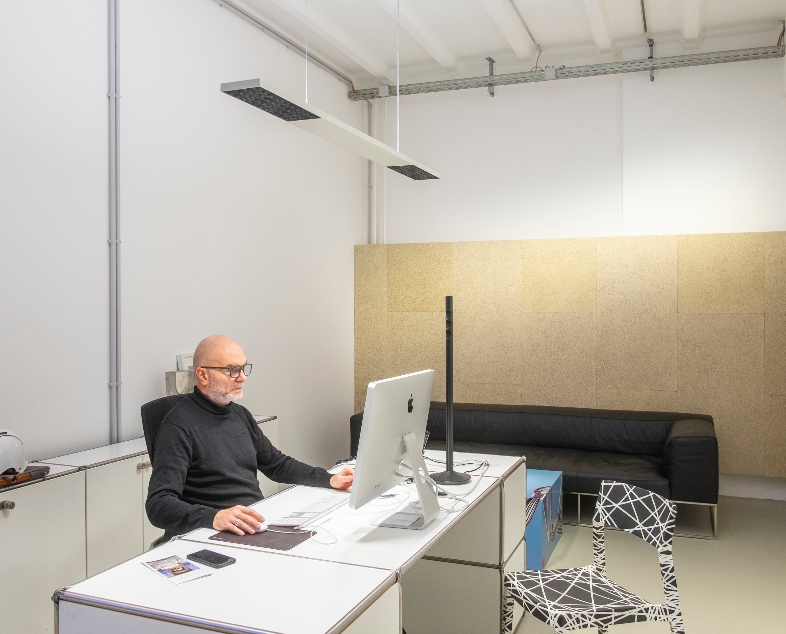 Mann arbeitet im Büro mit ERCO Jilly Downlights, die für flexible Bürobeleuchtung sorgen.