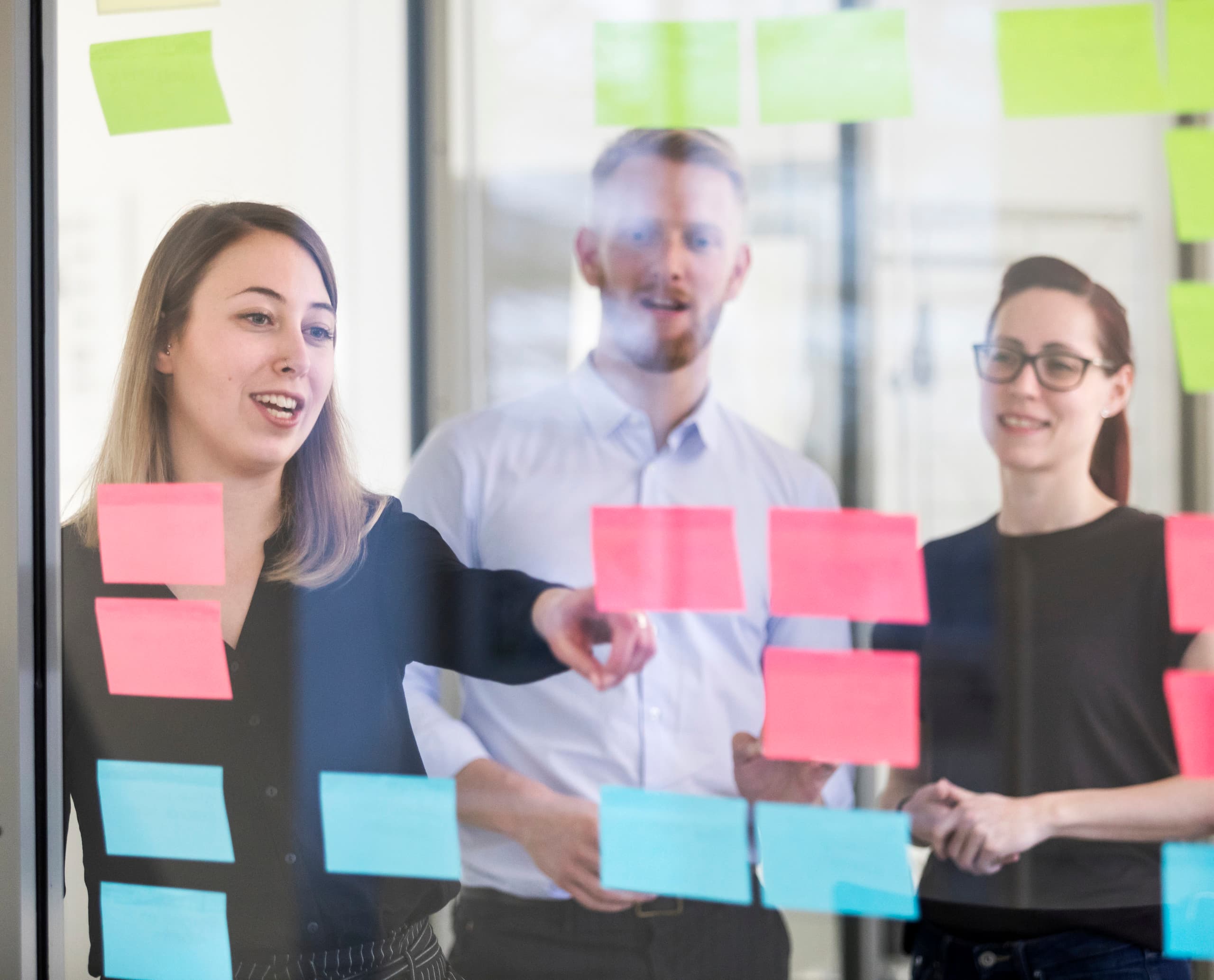 ERCO-Team bei der Ideenfindung mit Post-it Notizen an einer Glaswand im Büro.