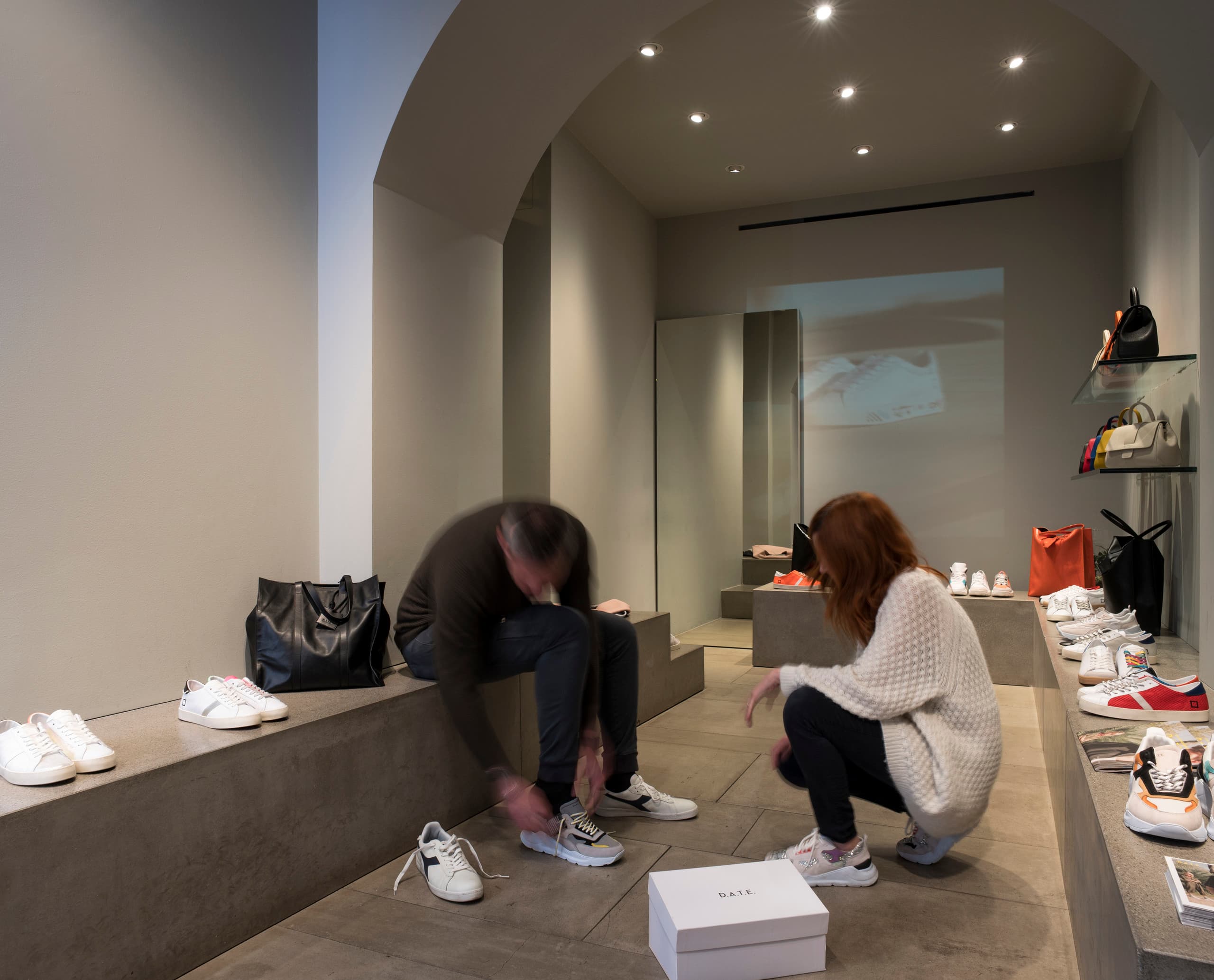 Kunden probieren D.A.T.E. Sneaker im Mailänder Flagshipstore, beleuchtet mit ERCO Strahlern.