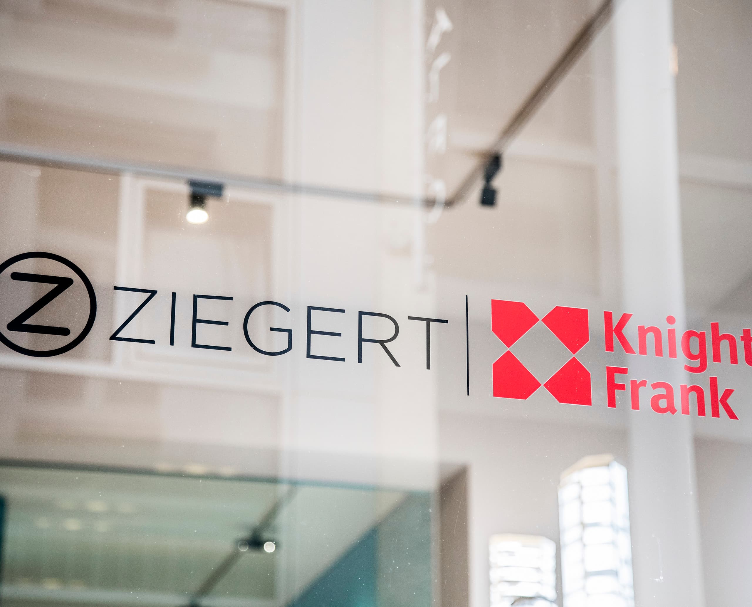ZIEGERT Knight Frank Logo auf Glas, ein Frankfurter Immobilienshop mit ERCO Licht.