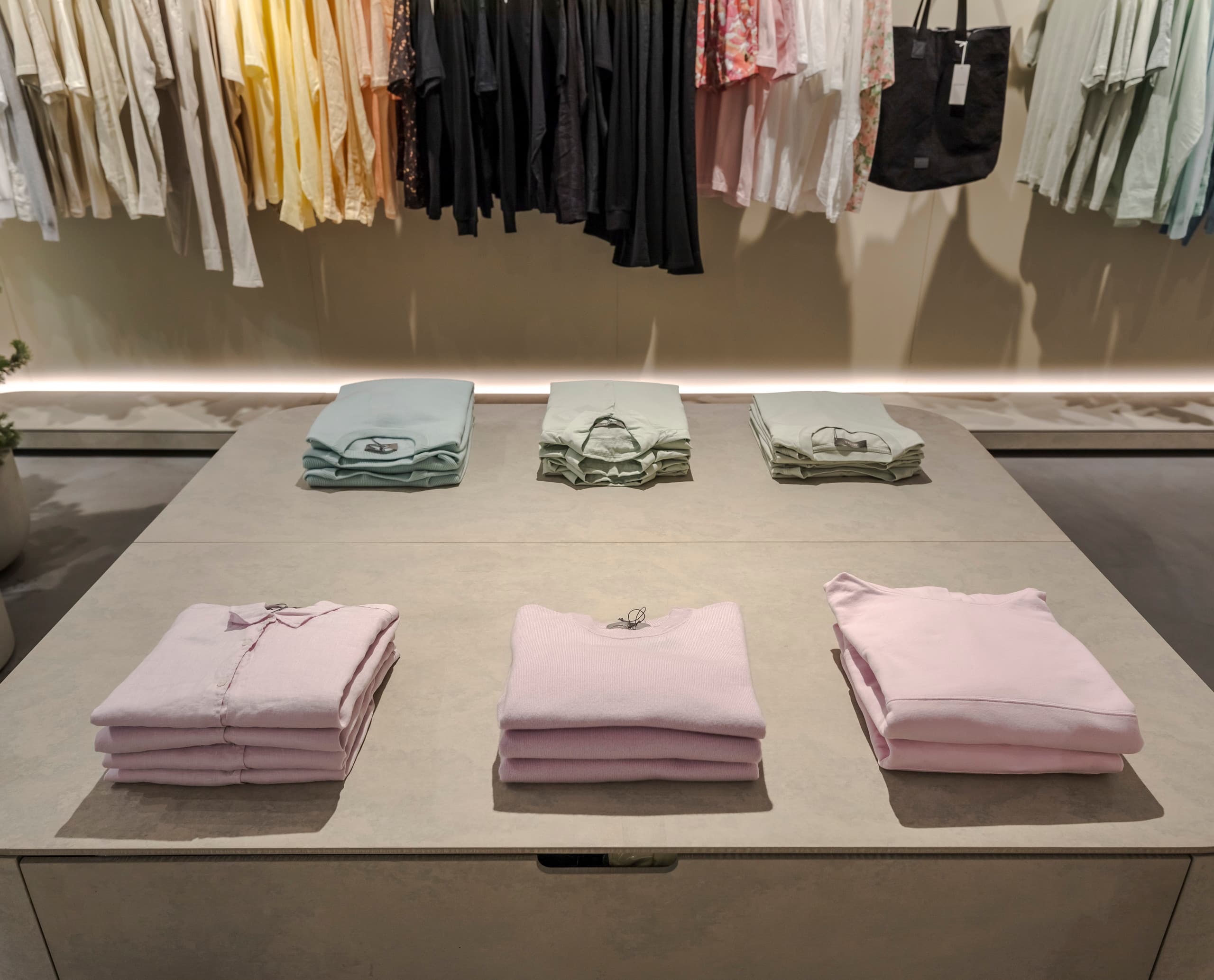 Gestapelte Kleidung im Jac + Jack Store, beleuchtet mit ERCO Optec Strahlern für präzise Farbwiedergabe.