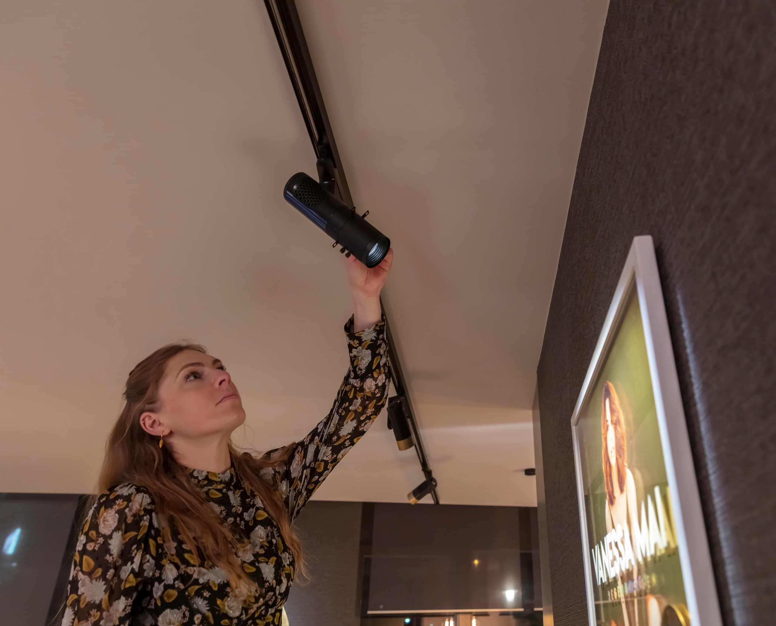 Frau justiert ERCO Konturstrahler zur Bildbeleuchtung in Galerie oder Museum.