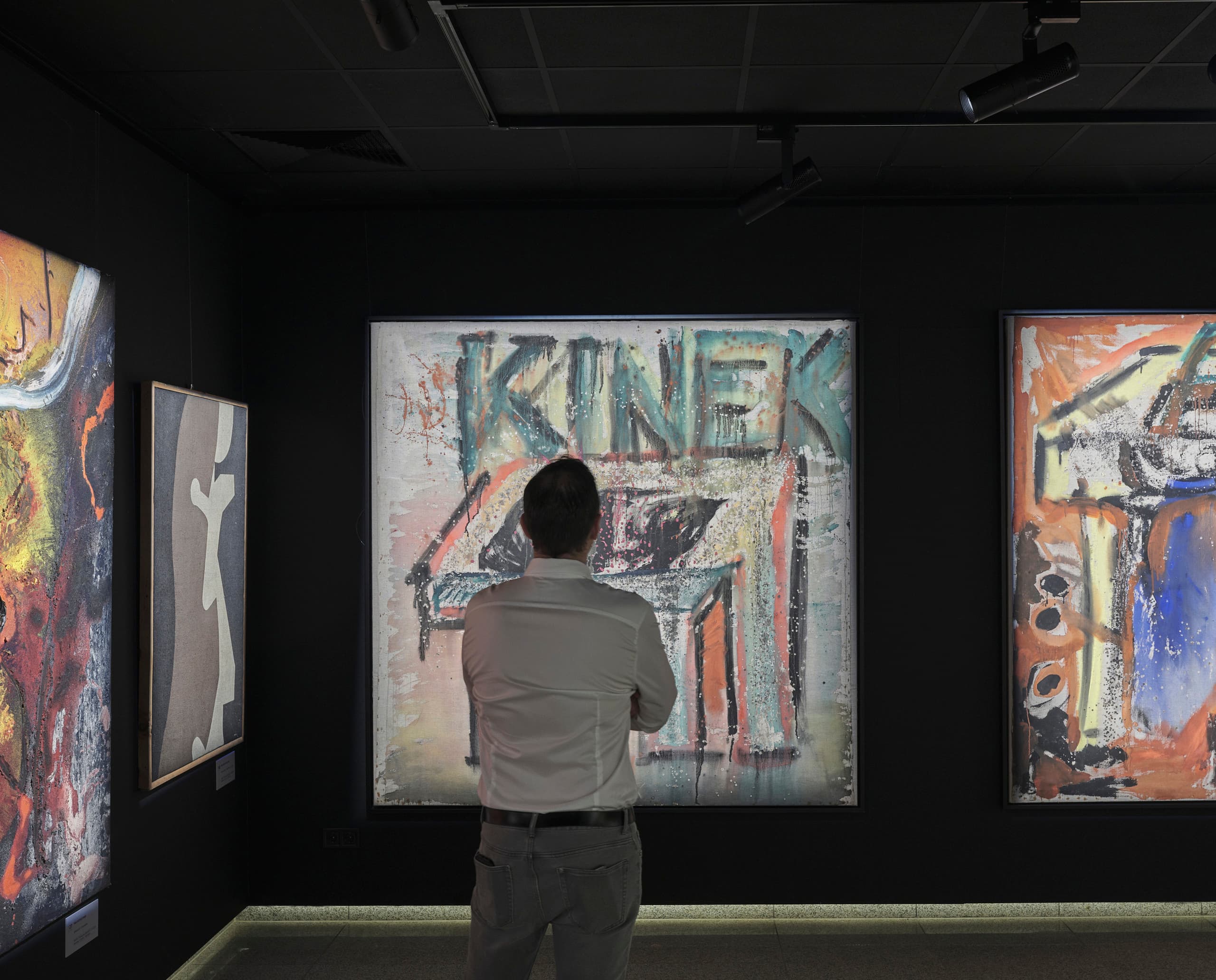 Mann betrachtet Kunstwerke in der Virág Judit Galerie, beleuchtet mit ERCO LED Strahlern.