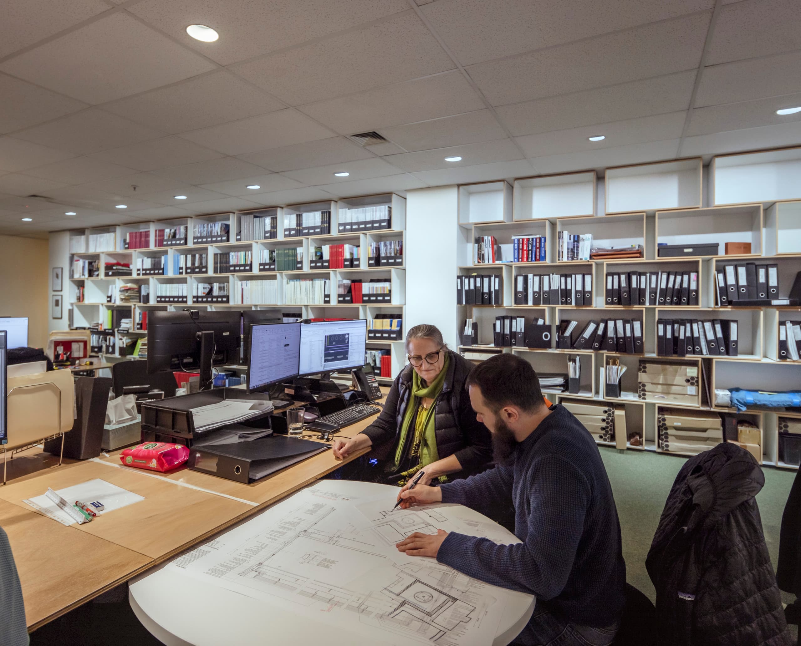 Lovell Chen Architektenbüro: Mitarbeiter besprechen Baupläne unter ERCO Downlights für Human Centric Lighting.