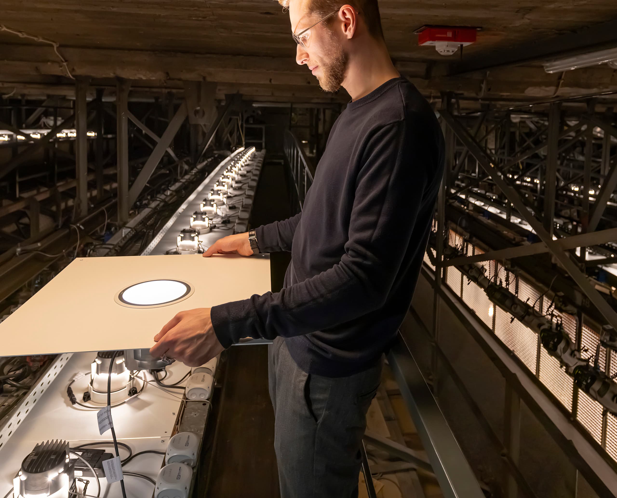 Ein Techniker installiert ERCO Atrium LED-Downlights in der Hamburger Staatsoper, um die Beleuchtung zu modernisieren.
