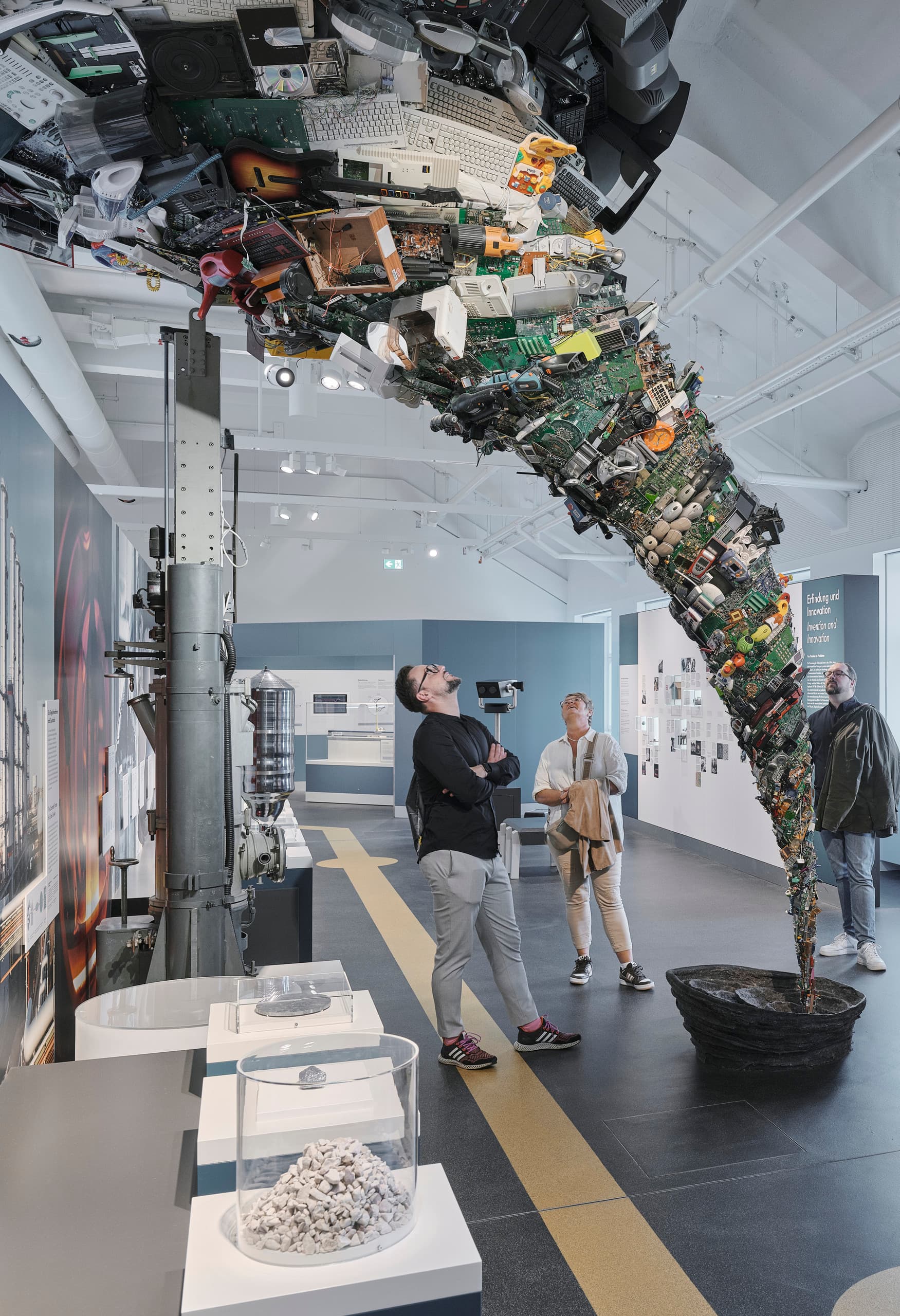 Besucher betrachten eine Skulptur aus Elektroschrott im Deutschen Museum, beleuchtet mit ERCO LED-Strahlern.