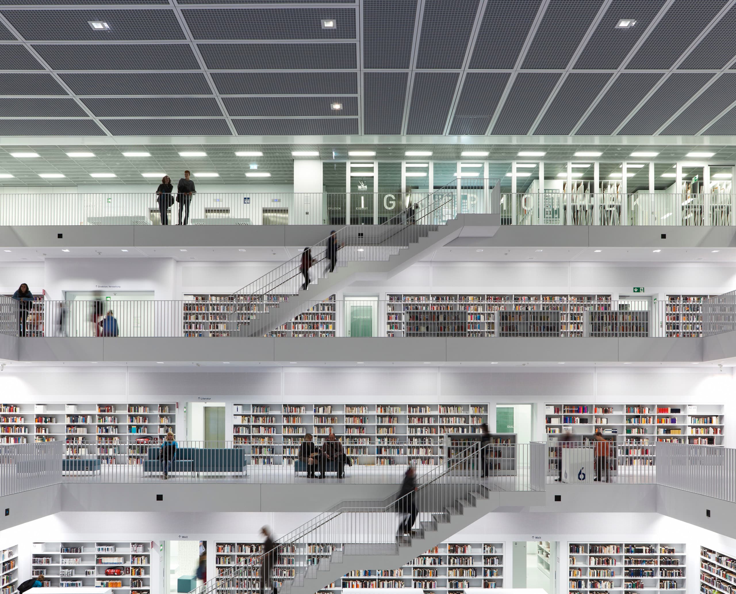 Bibliothek 21 in Stuttgart: Mehrstöckige Halle mit Bücherregalen und Treppen, beleuchtet mit ERCO Licht.
