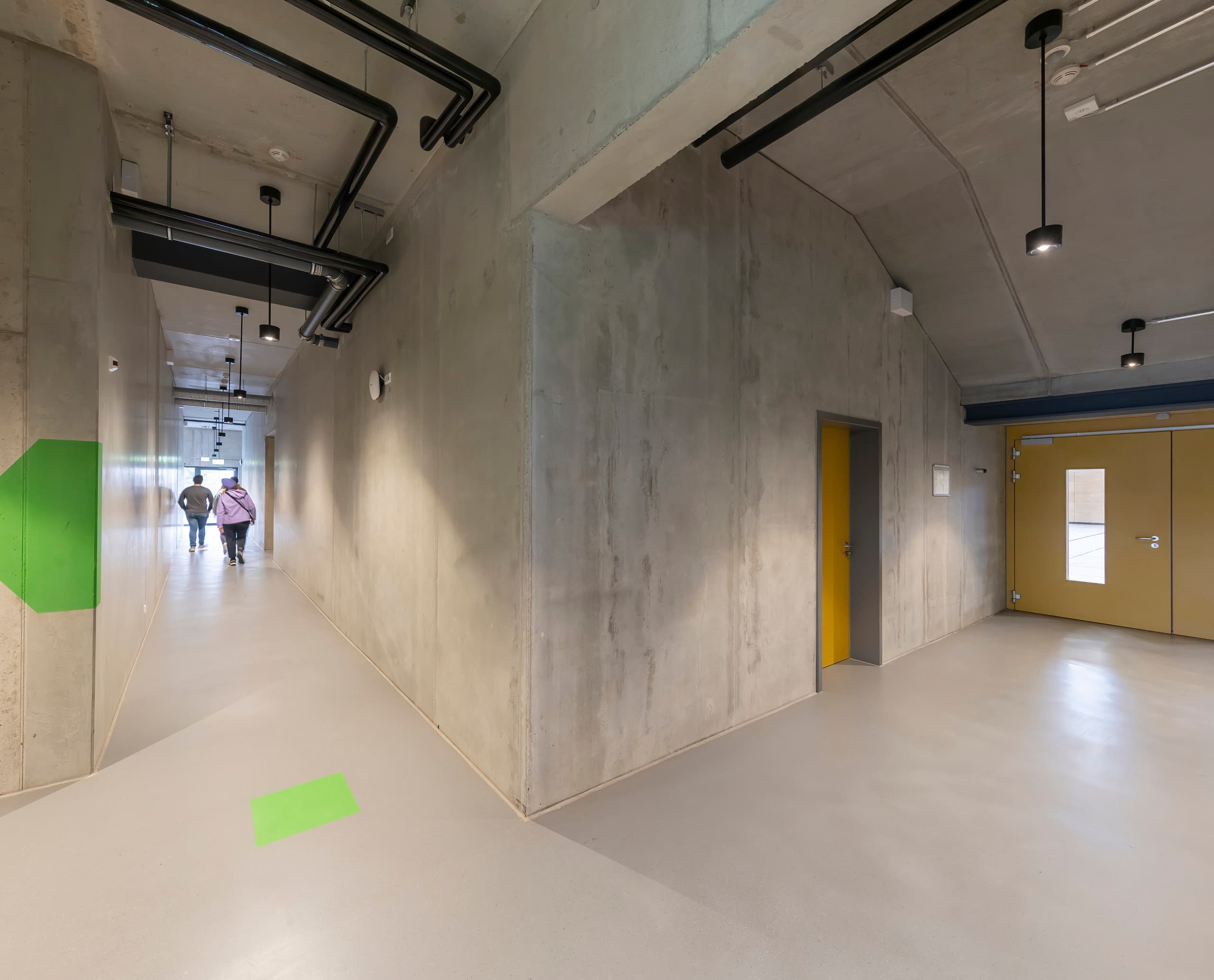Flur im Gymnasium Neustadt mit ERCO Skim Downlights für gleichmäßige Ausleuchtung.