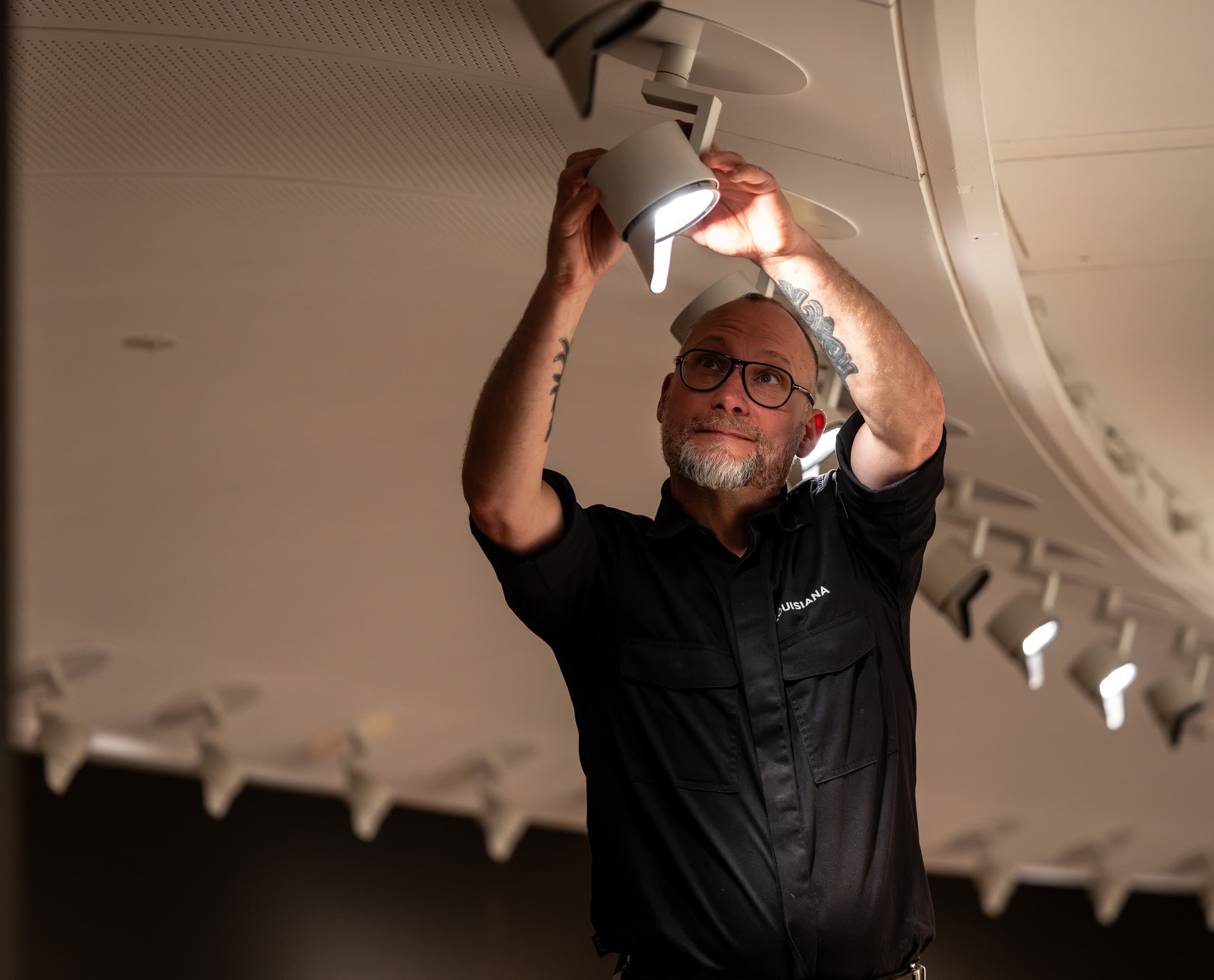 Ein Mann justiert einen ERCO Parscan LED-Strahler im Louisiana Museum, um die Ausstellungsbeleuchtung zu optimieren.