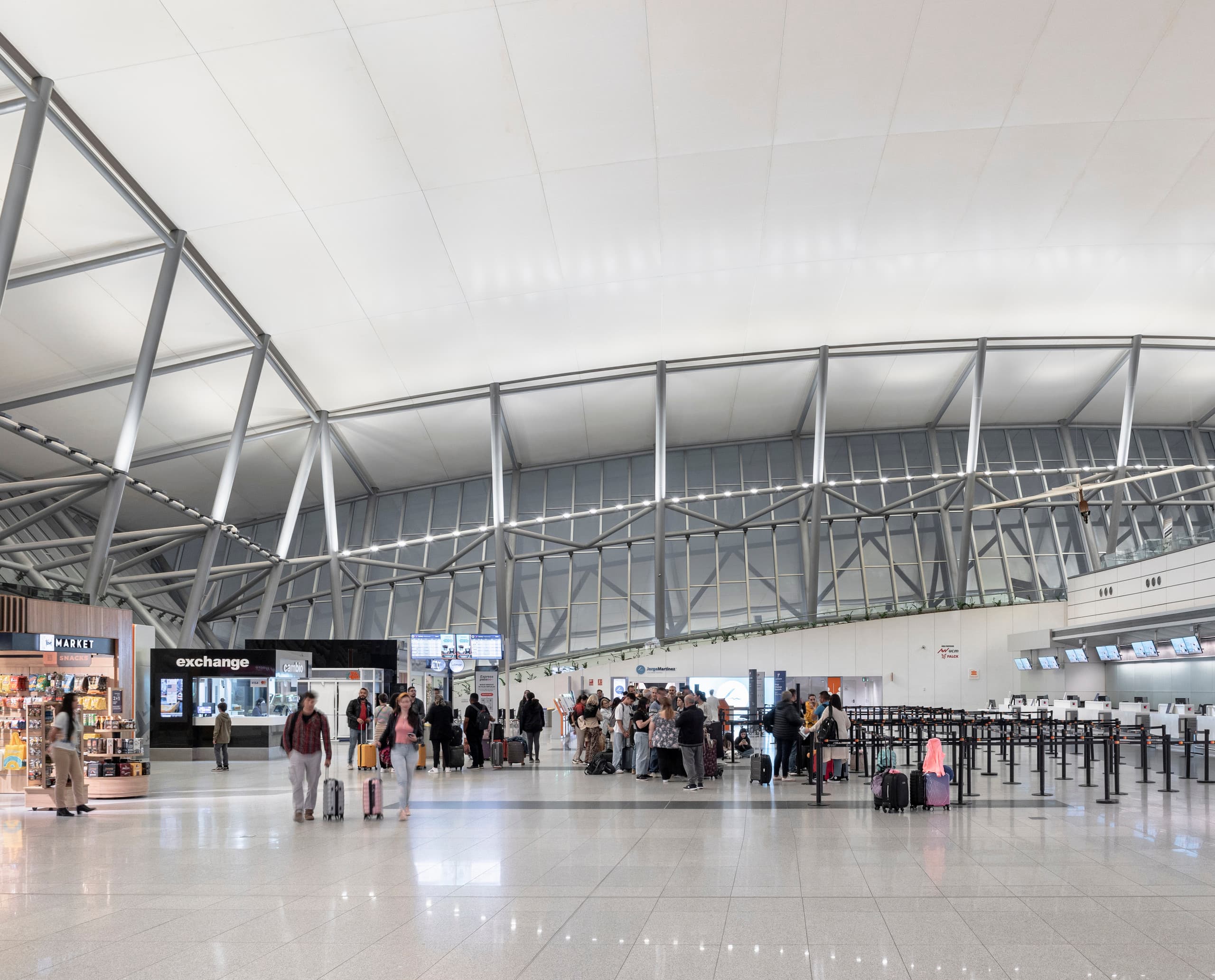Flughafen Carrasco Terminal mit ERCO LED-Beleuchtung und Passagieren.