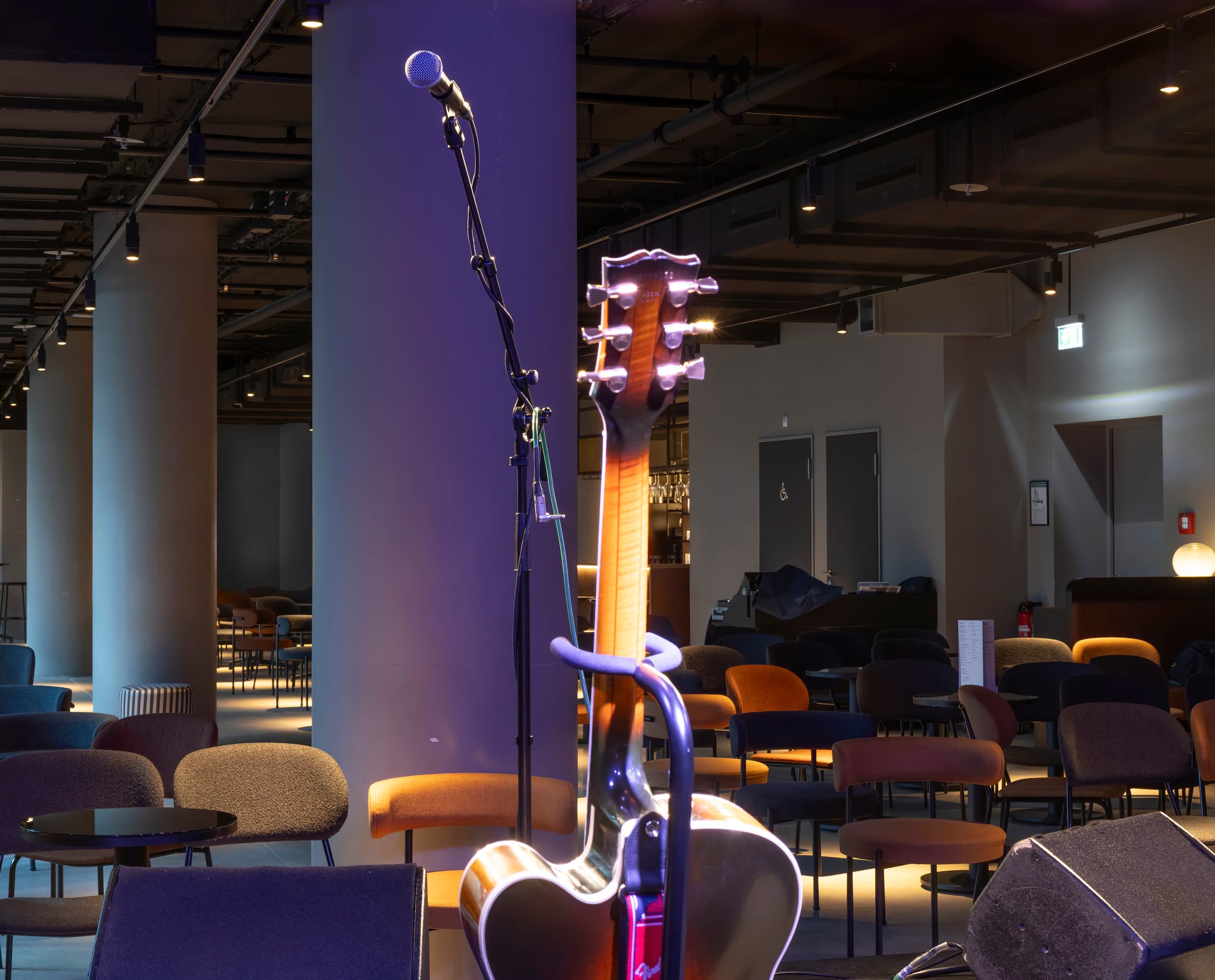 Akustikgitarre und Mikrofon auf der Bühne des NICA Jazz Club, beleuchtet mit ERCO Strahlern.