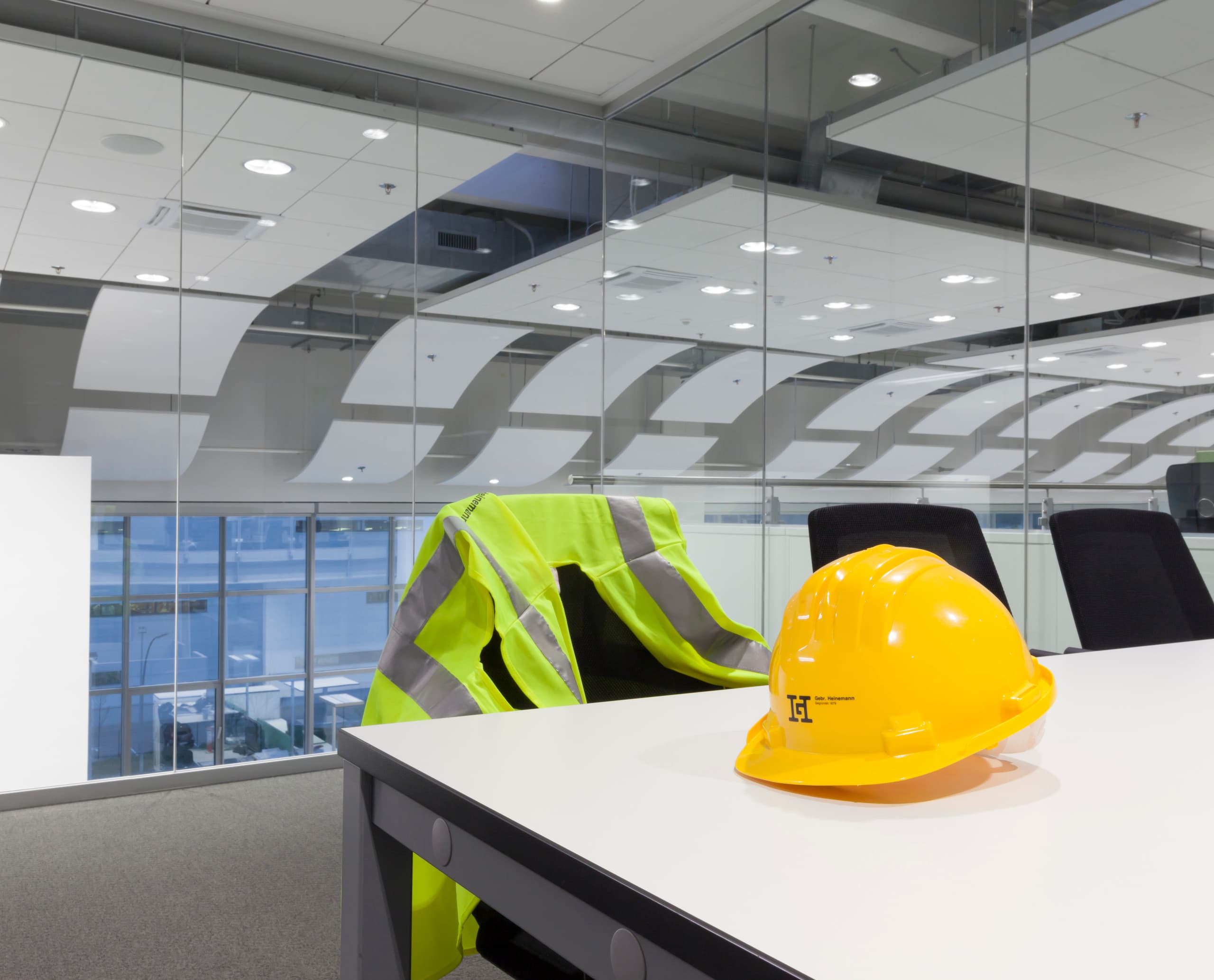 Gelber Schutzhelm und Warnweste im Gebrüder Heinemann Büro, Hamburg. ERCO LED Downlights für effiziente Bürobeleuchtung.