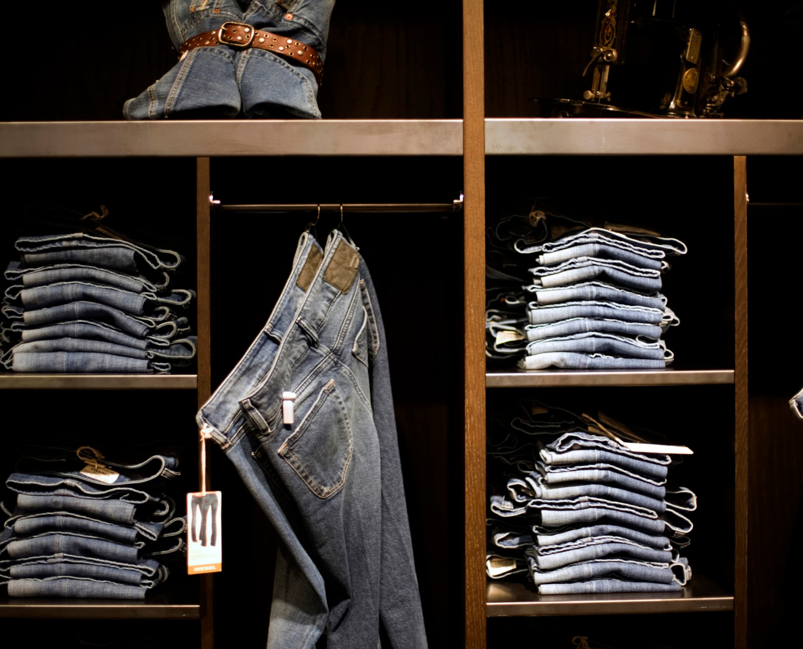 Diesel Jeans im Regal, gefaltet und hängend, Teil der modernen Ladenbeleuchtung im Mailänder Flagship Store.