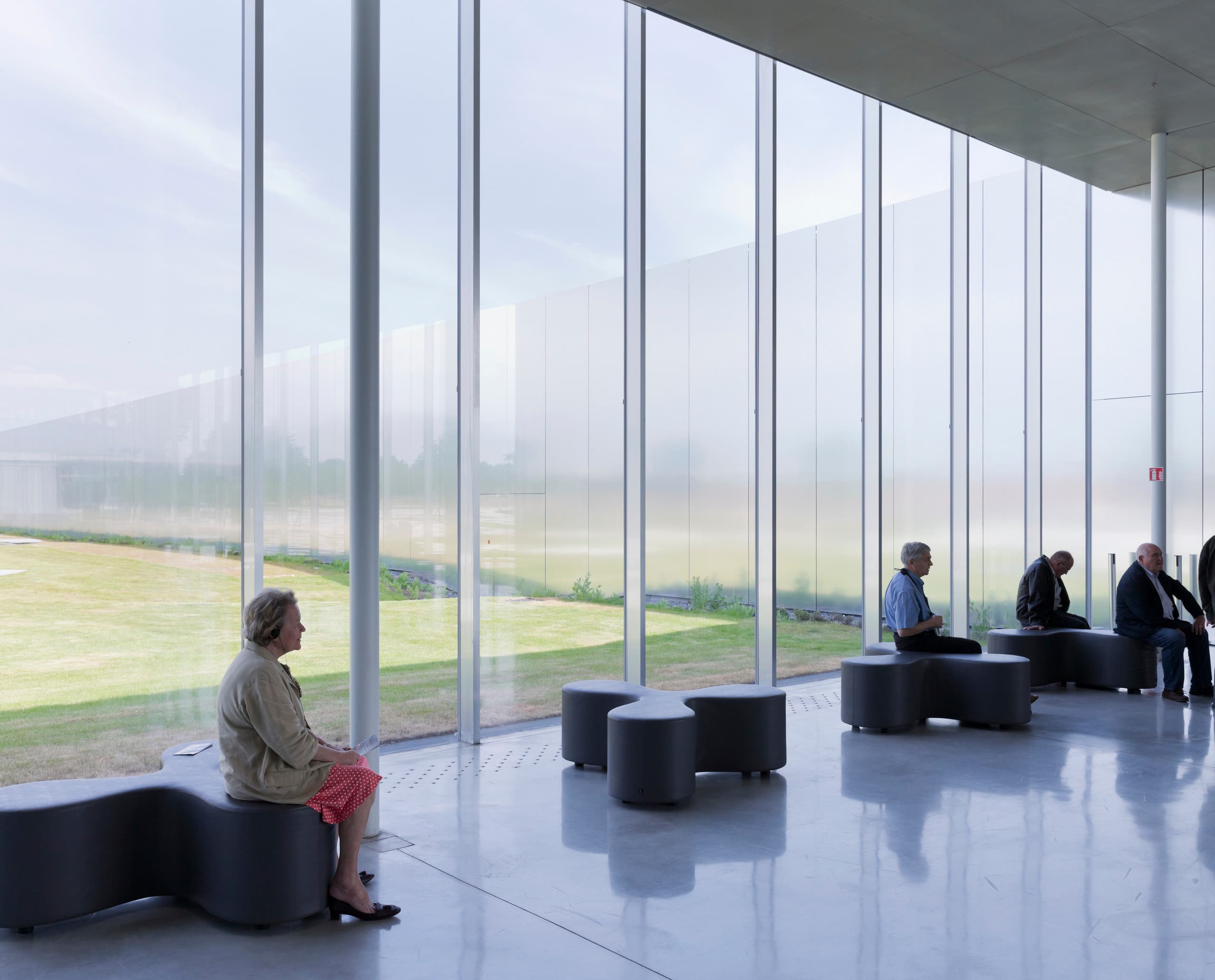 Besucher sitzen auf Bänken im Louvre Lens Museum, beleuchtet mit ERCO LED-Leuchten.