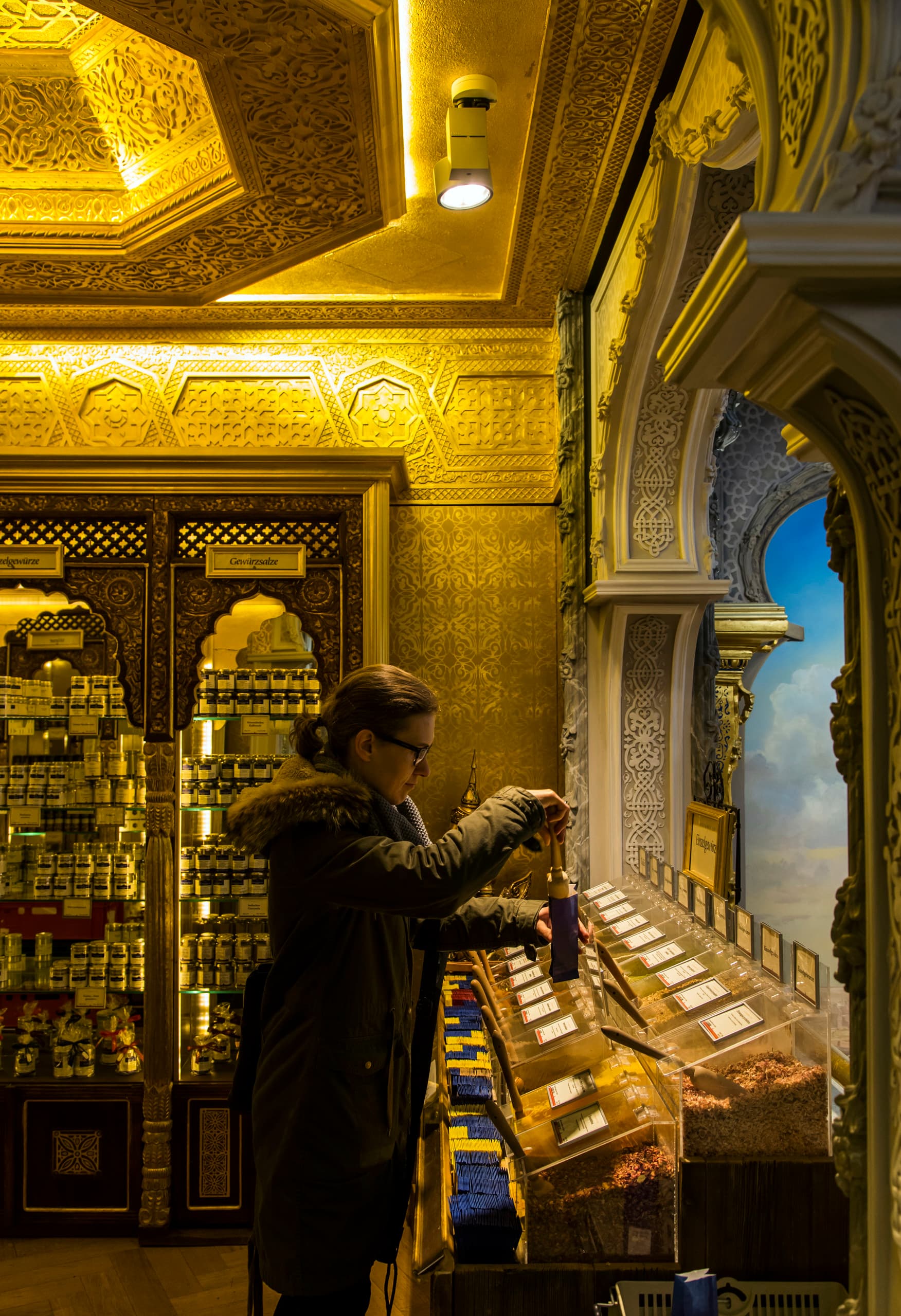 ERCO LED-Beleuchtung im Schuhbecks Gewürzladen, München. Kundin wählt Gewürze im orientalischen Design.