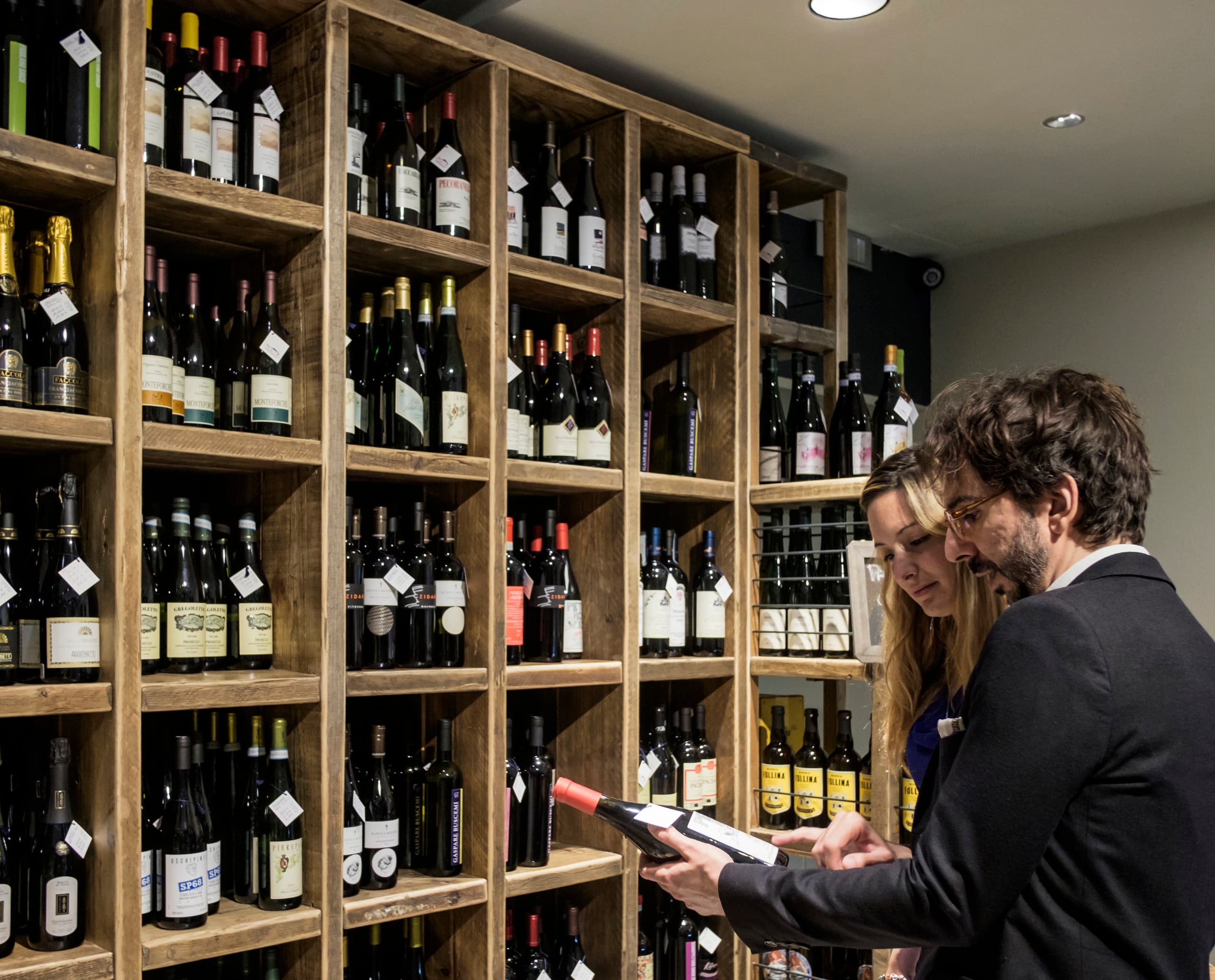 Kunden wählen Wein in der Feinkosthandlung Fiorital, beleuchtet mit ERCO LED-Lichtern.
