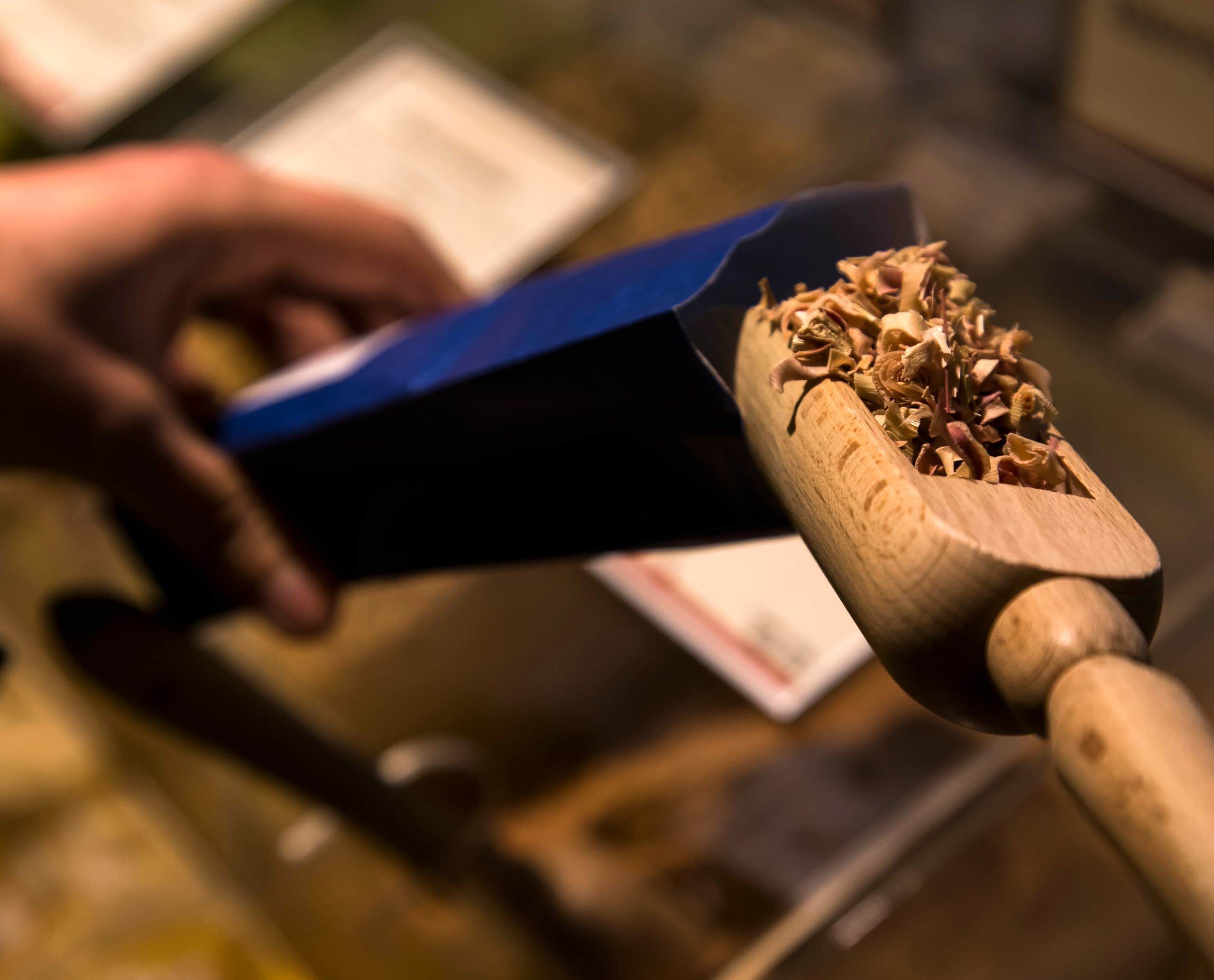 Schuhbecks Gewürze: Kunde schöpft mit Holzschaufel Gewürze ab, beleuchtet mit ERCO LED-Licht.