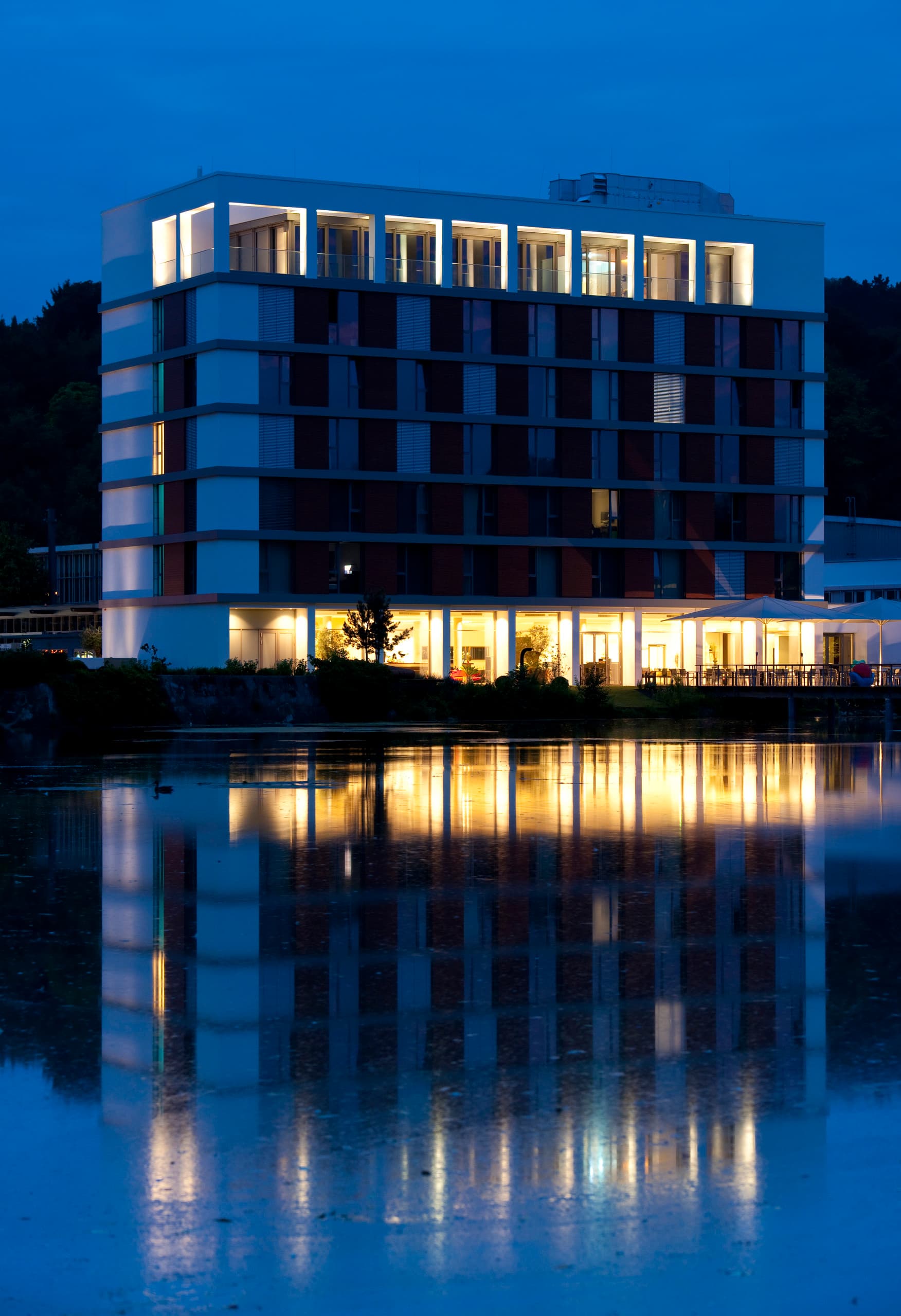 LAGO Hotel in Ulm, ein stilvolles Gebäude mit sanfter Beleuchtung am See.