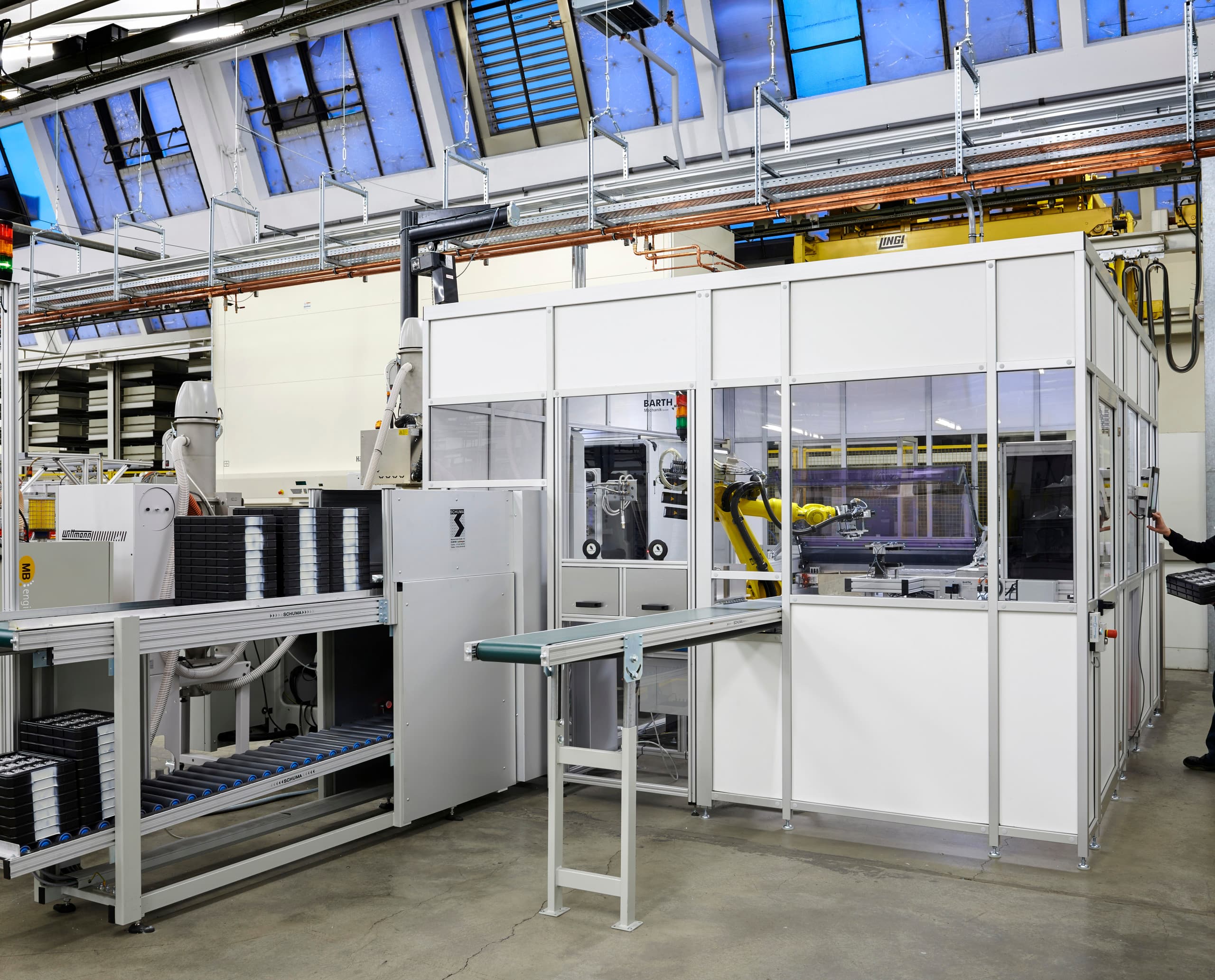 ERCO LED-Linsen Produktion: Automatisierte Fertigungszelle mit Industrieroboter für präzise optoelektronische Tests.