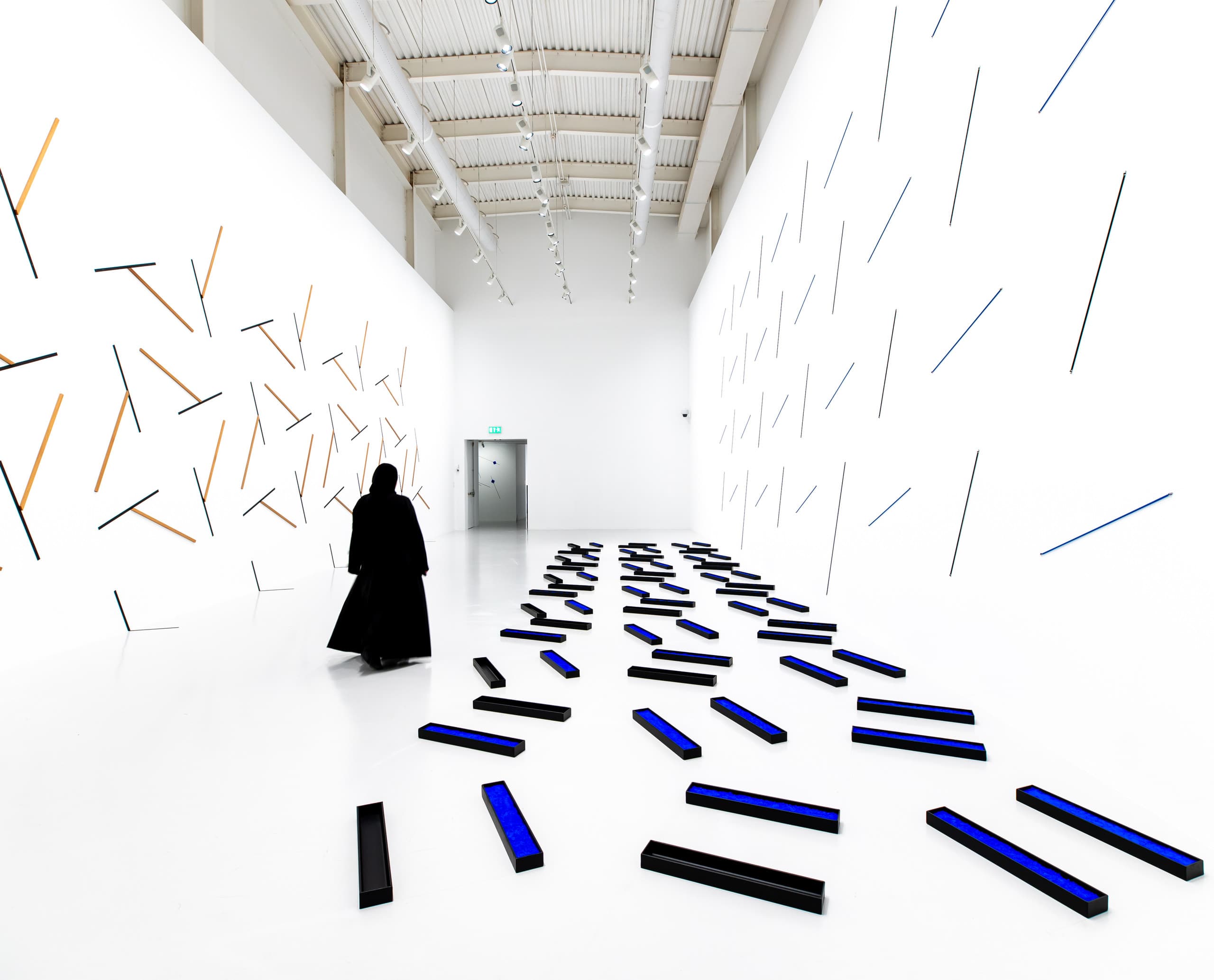 Weißer Ausstellungsraum mit blauen und schwarzen Brettern.
