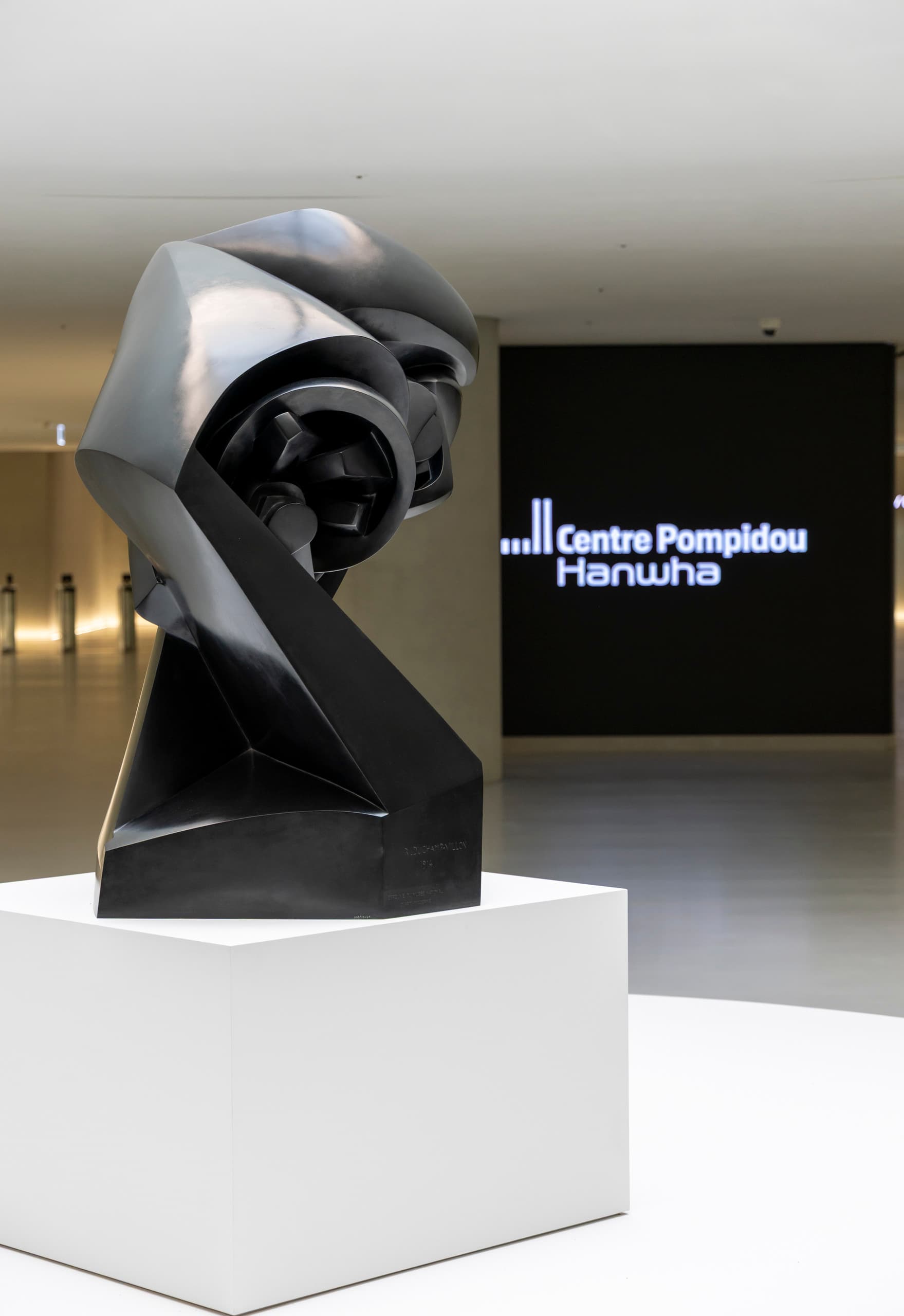 Schwarze Skulptur mit LED Leinwand im Hintergrund.