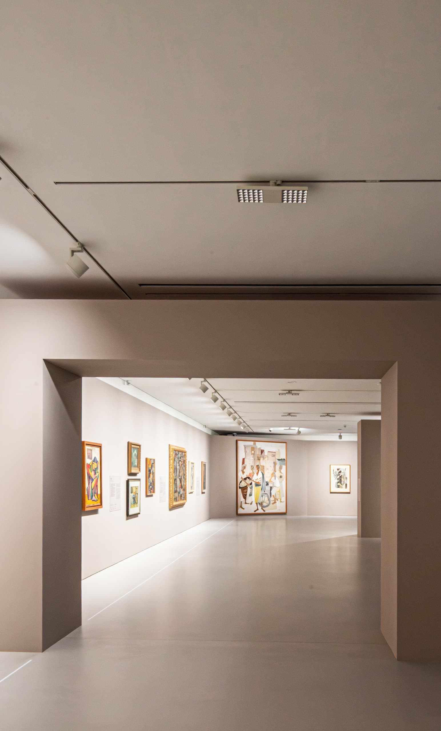 Ausstellungsraum mit beige-farbenem Bogen und Bildern an den Wänden.