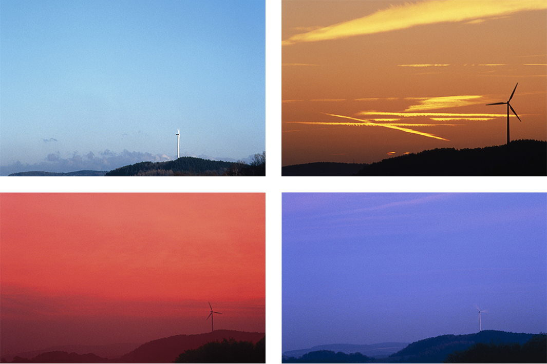 Berg med vindkraftverk framför en mörk himmel. Berg med vindkraftverk framför en ljusblå himmel. Berg med vindkraftverk framför en rödaktig himmel. Berg med vindkraftverk framför en solnedgång.